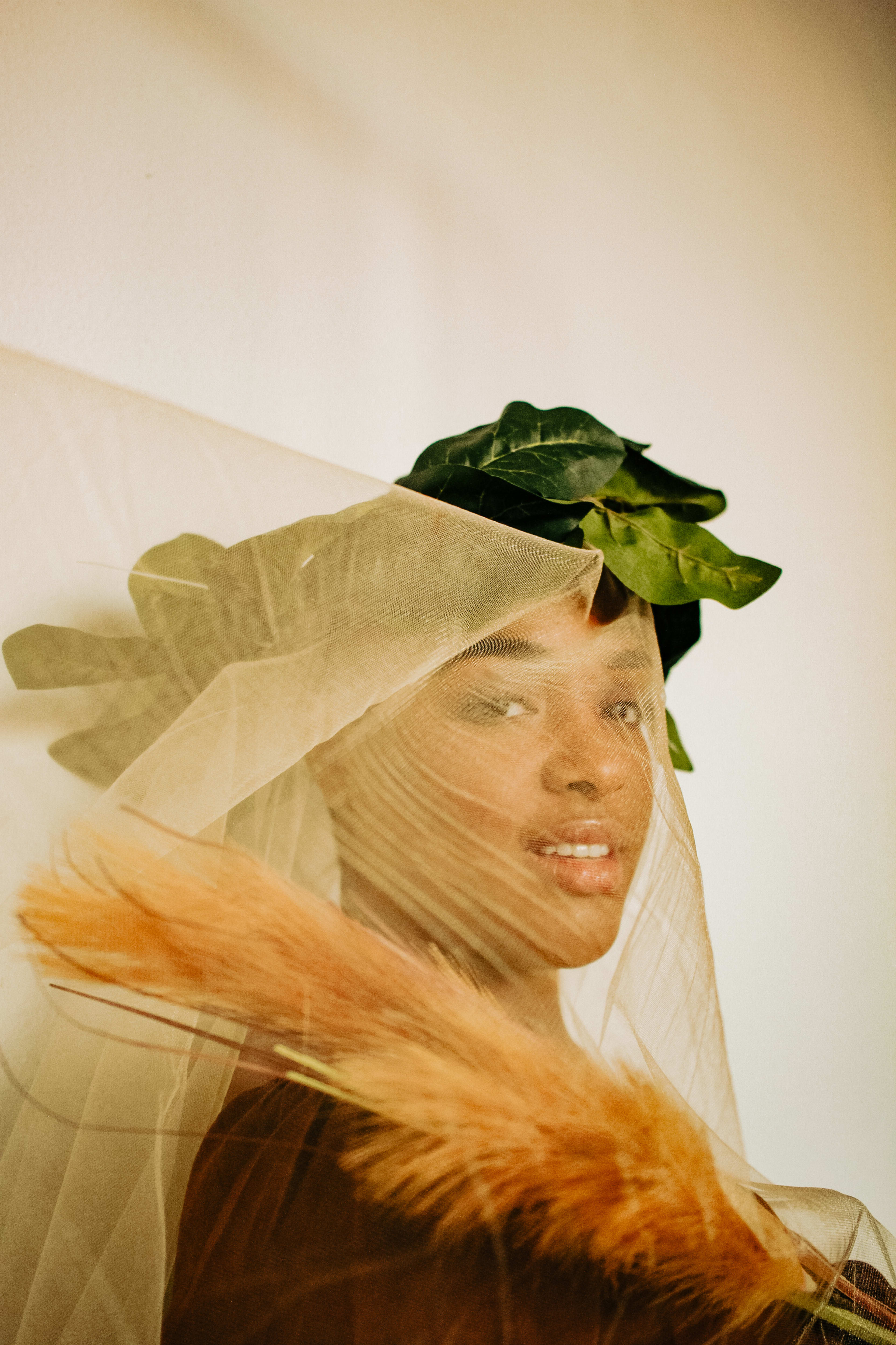 A person in a beige veil and green leaf headpiece at a photo shoot.
