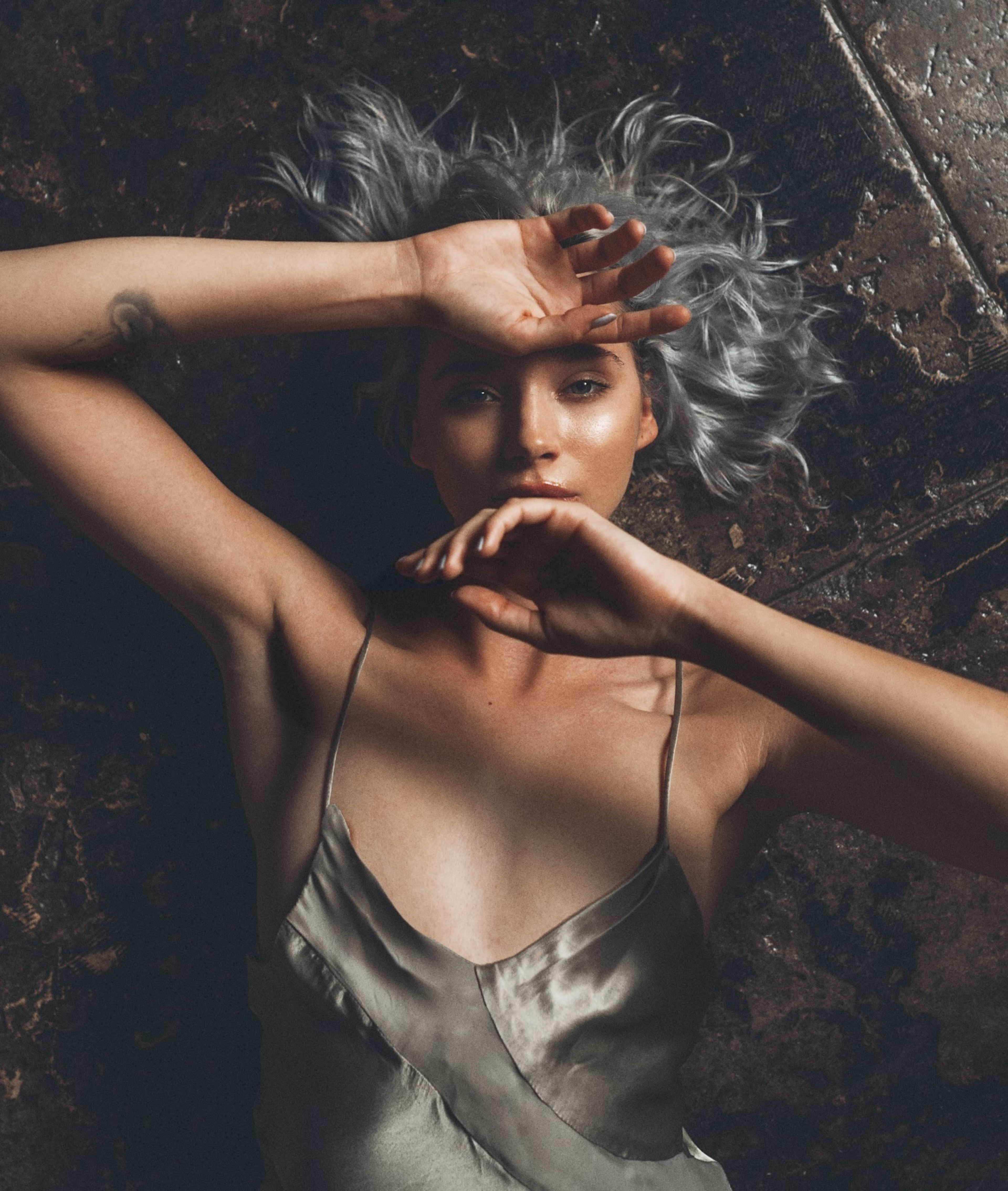 A fashion-conscious woman with grey hair is posing for a photo shoot.