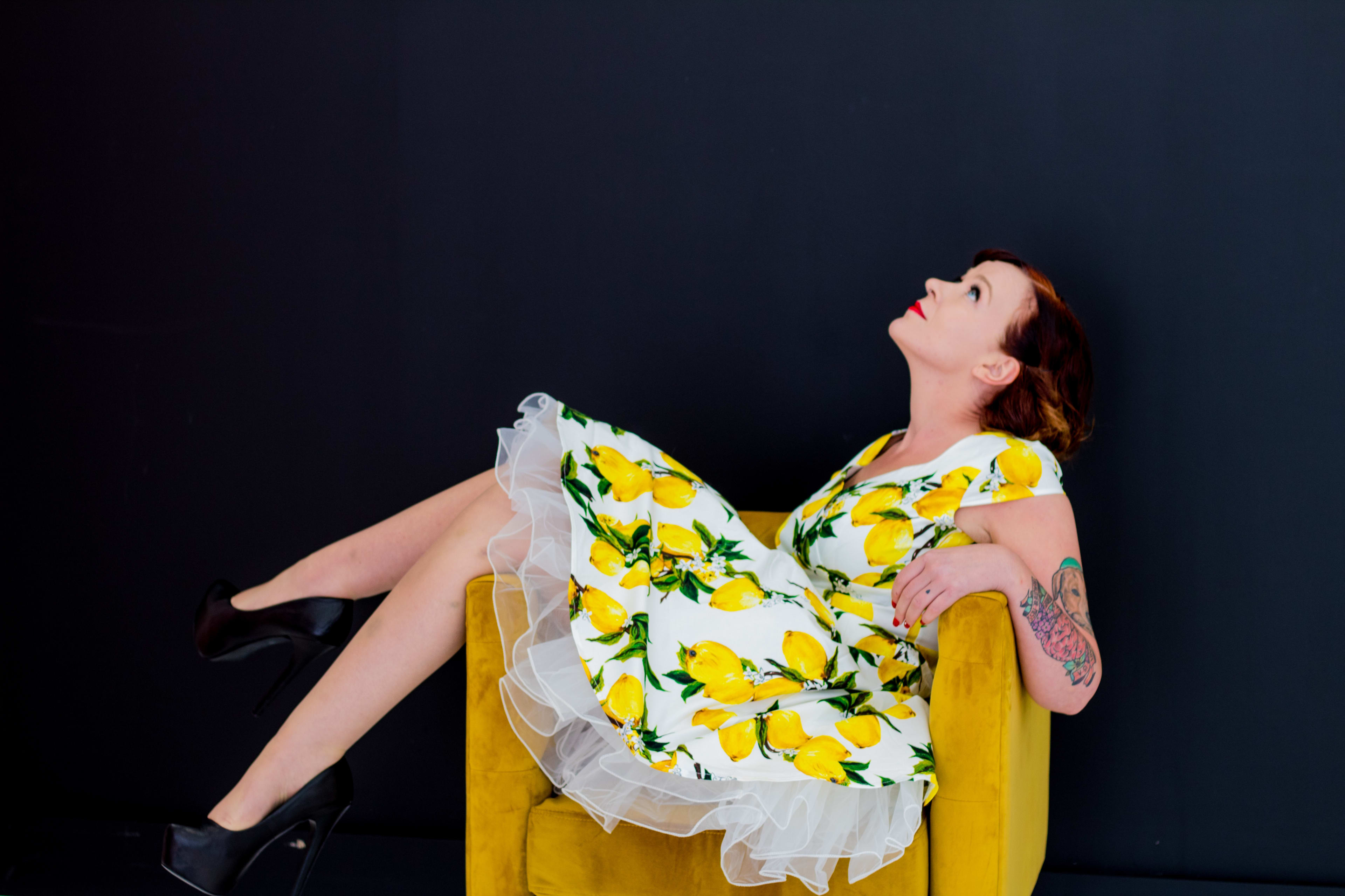 A woman in a yellow lemon dress posing for a fashion photo shoot.