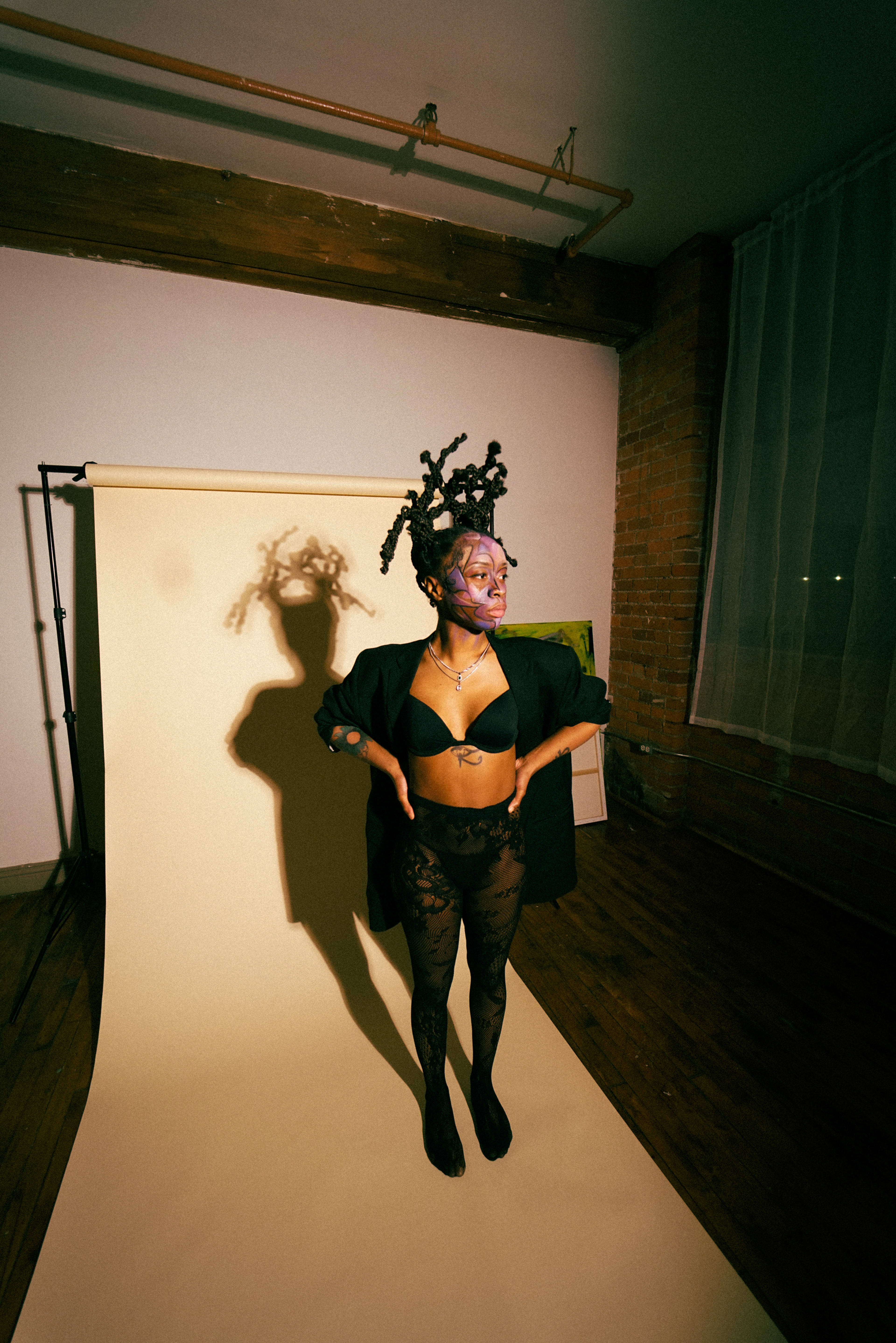 A woman is standing in front of a white backdrop for a photoshoot.