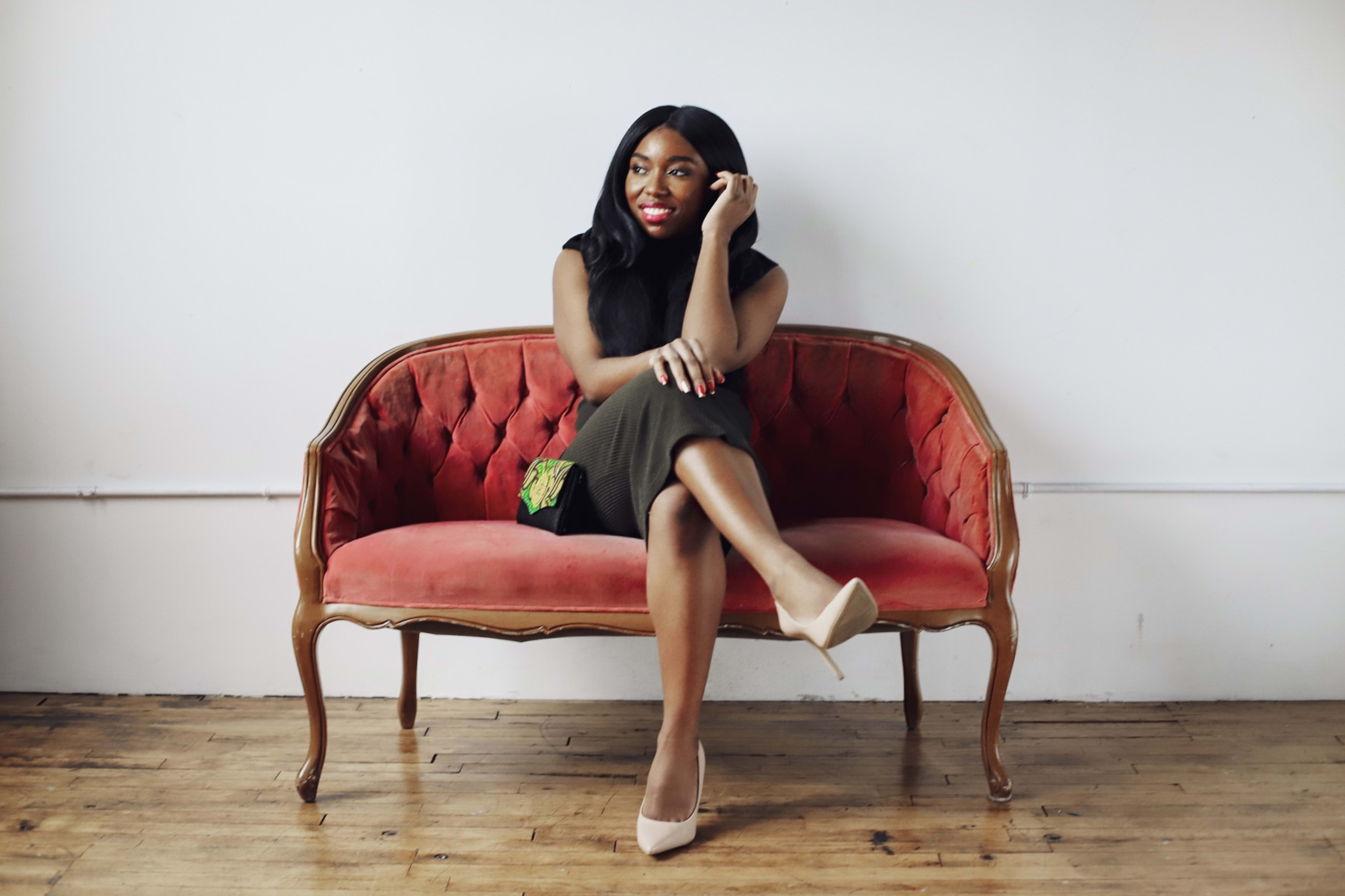 A photoshoot of a woman on a red velvet couch.