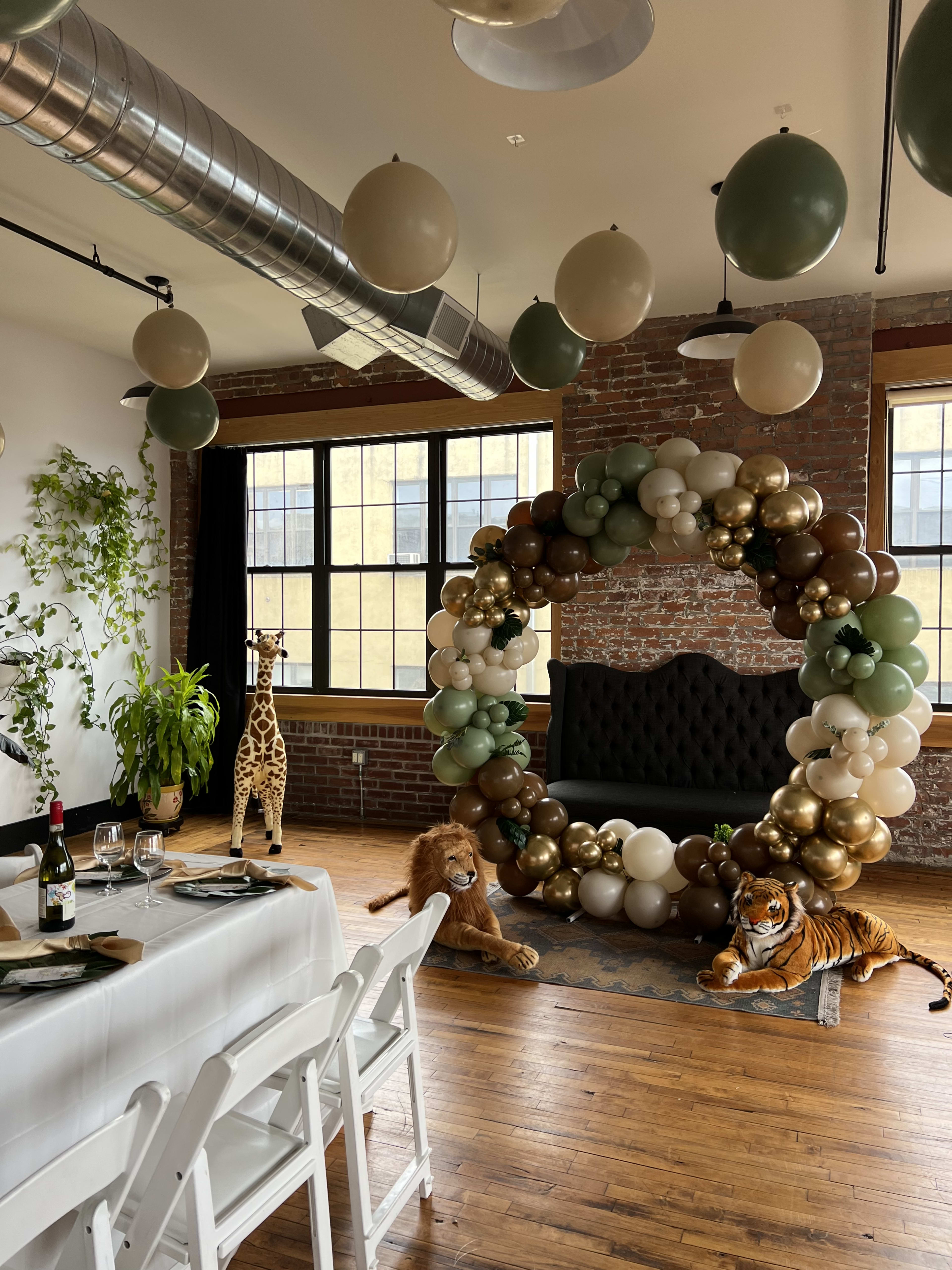 Una habitación con un montón de globos verdes colgando del techo para un baby shower de género neutro.