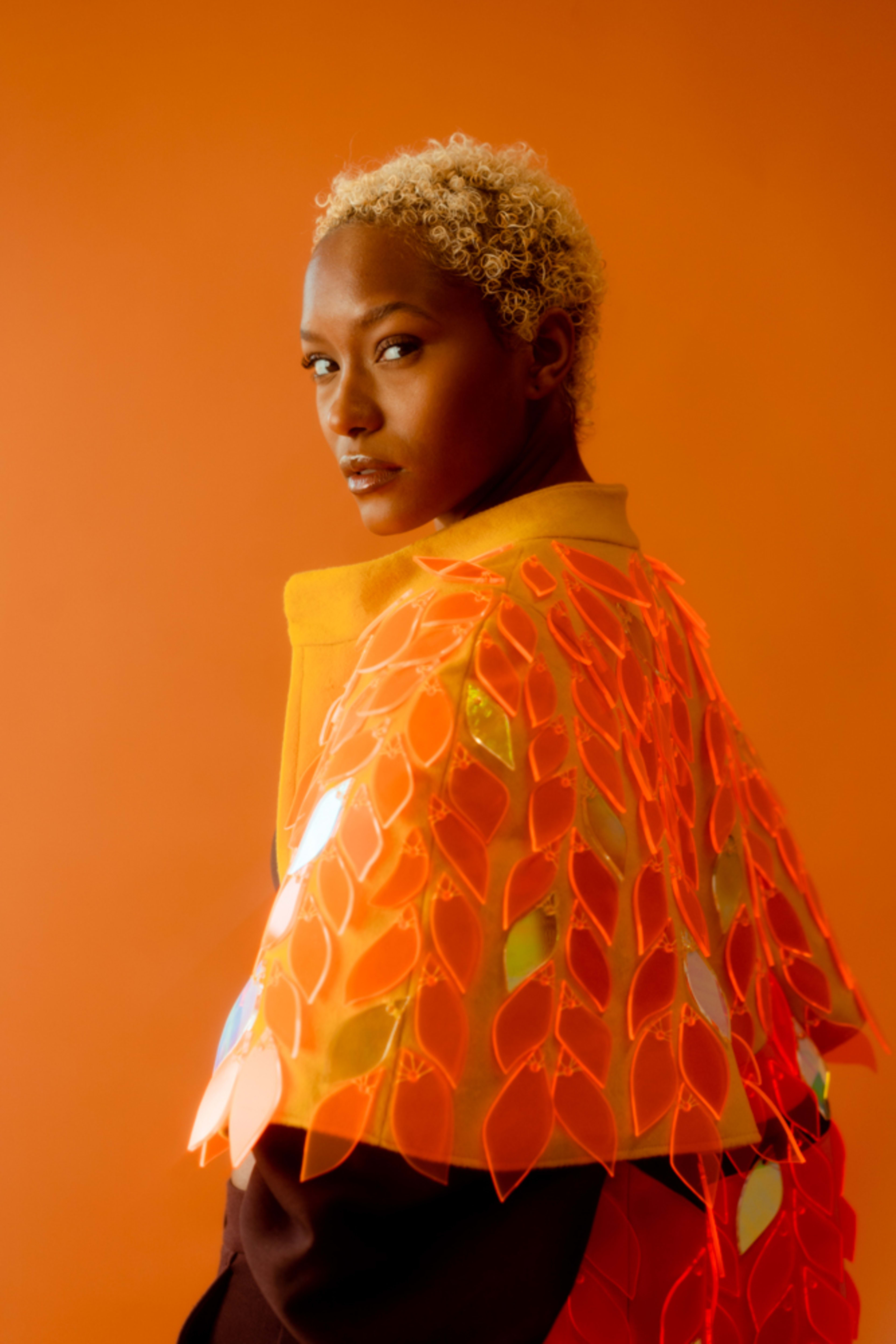 A fashion model in an orange themed photoshoot.
