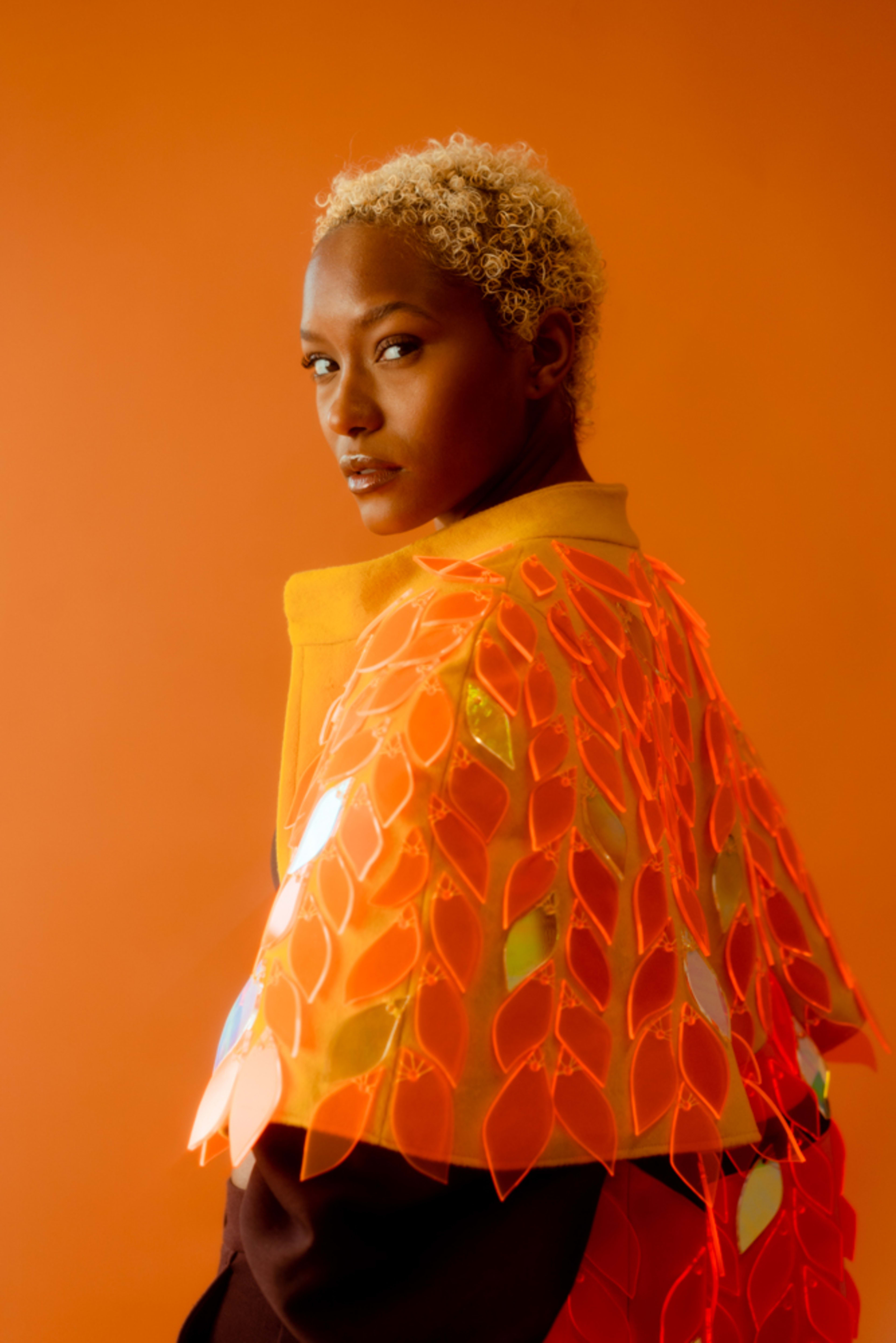 A fashion model in an orange themed photo shoot.