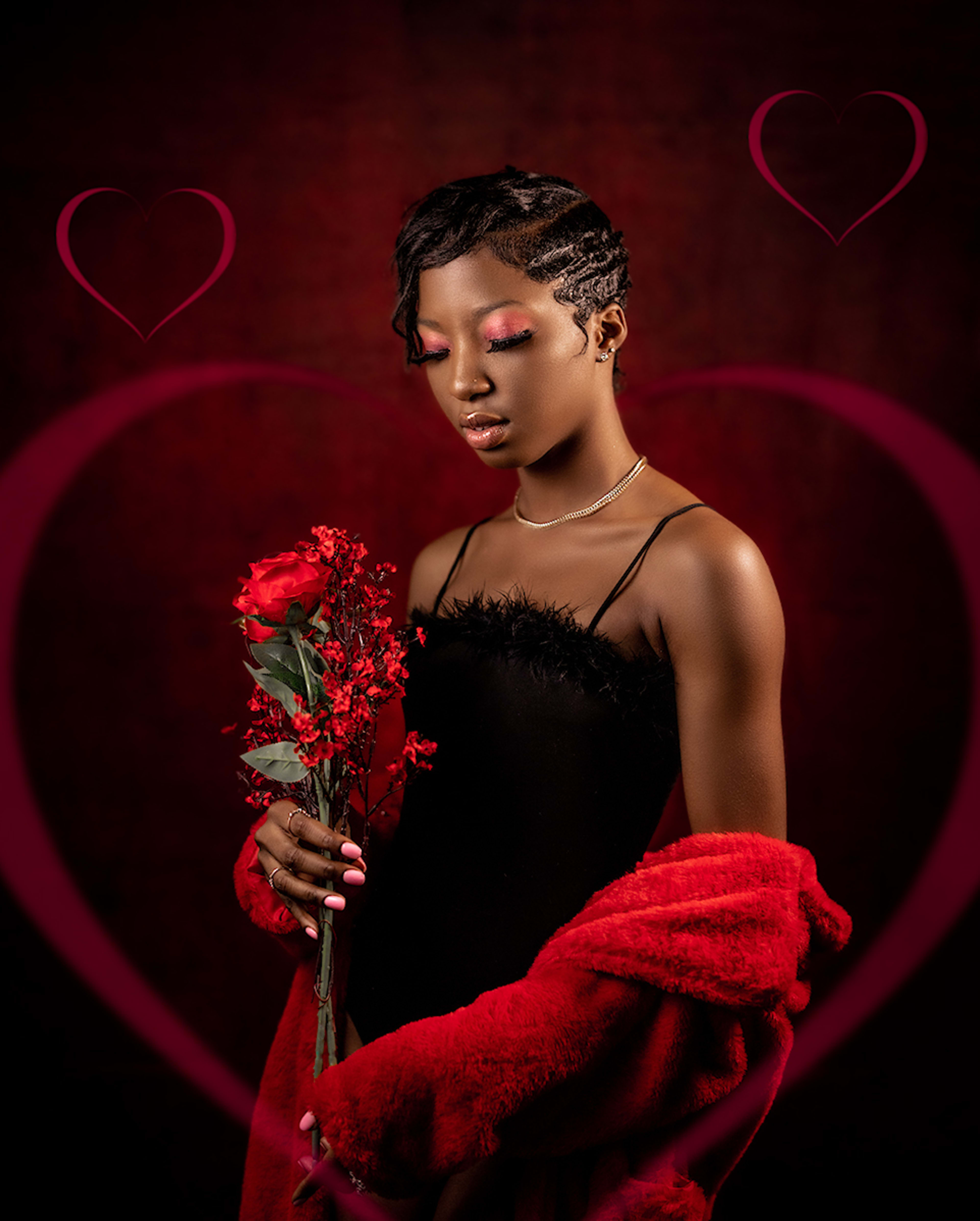 Eine Frau in einem schwarzen Kleid posiert für ein Fotoshooting mit einem Strauß roter Blumen.