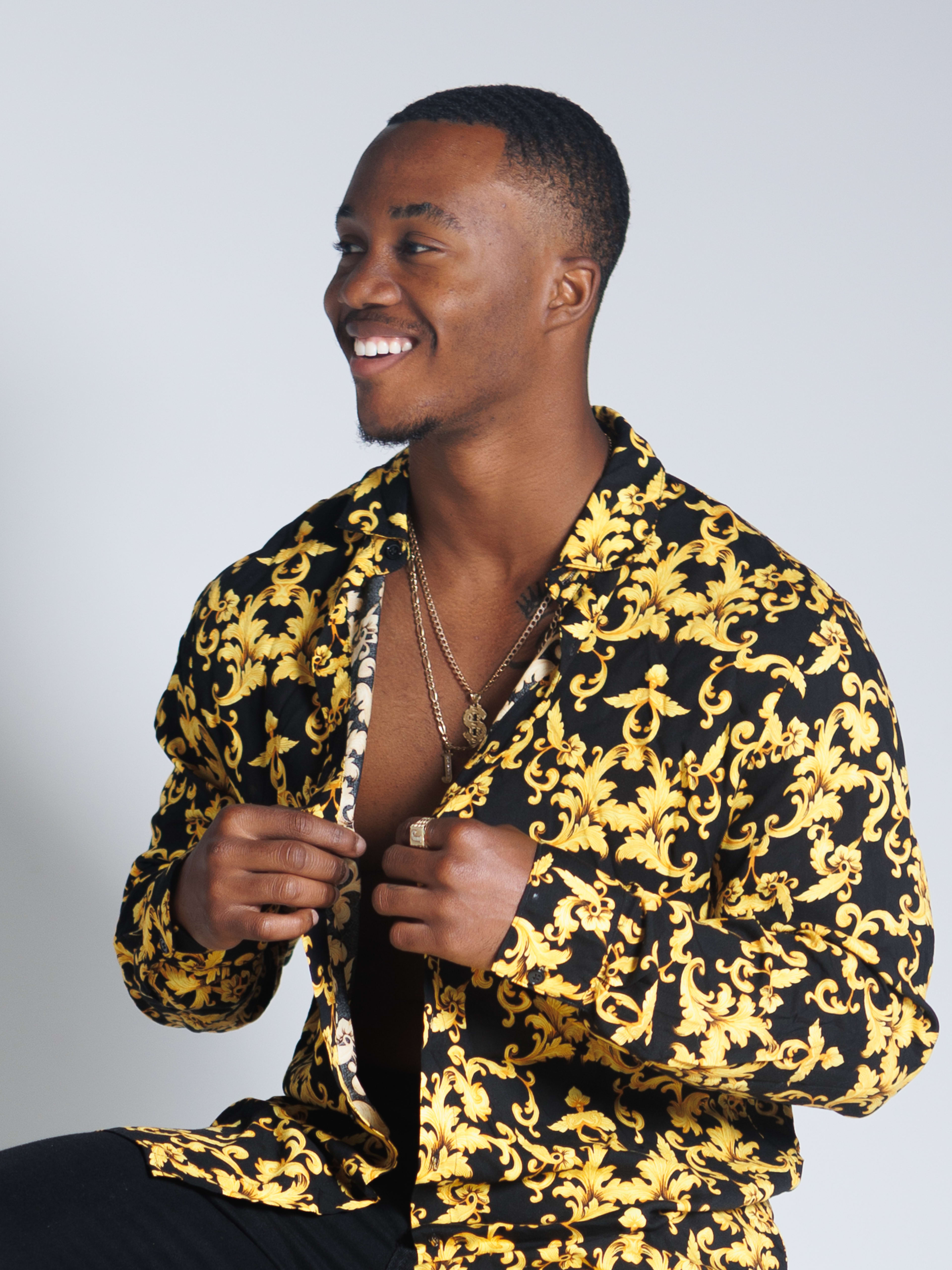 A man posing in yellow and black during a fashion photo shoot.