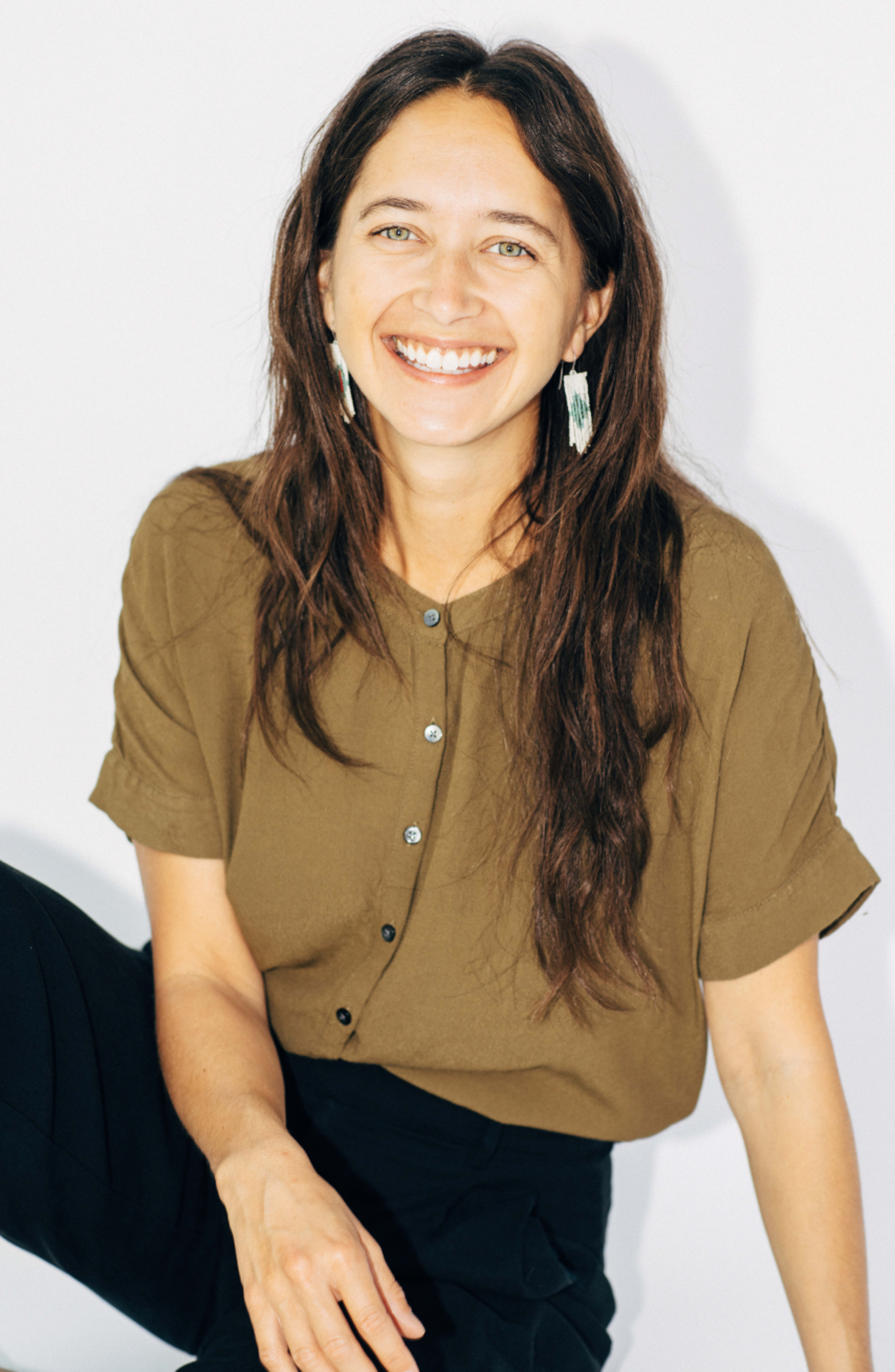 Une femme assise au sol souriant pour l'appareil photo.