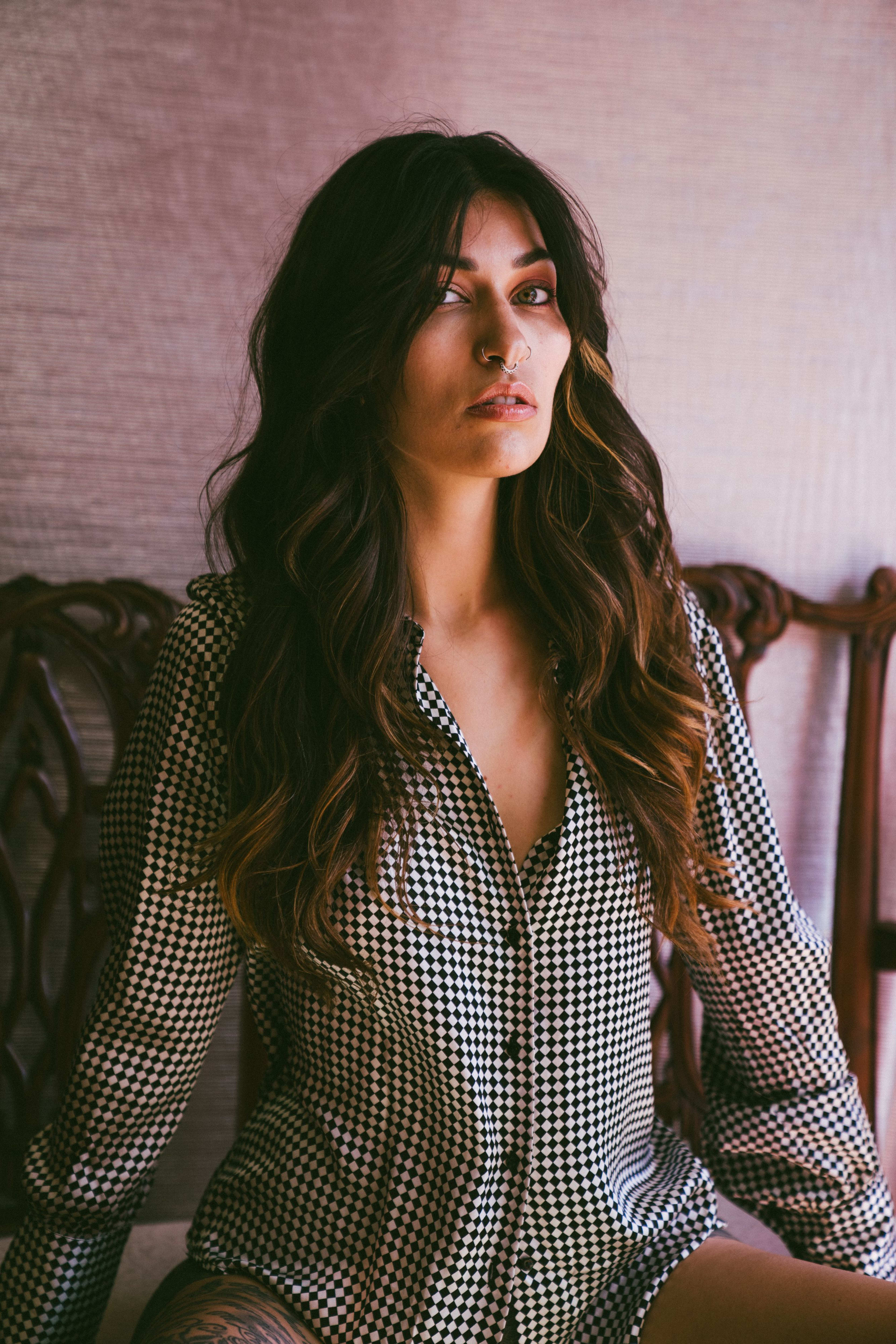 A woman in a plaid shirt posing for black and white photoshoot on the bed.