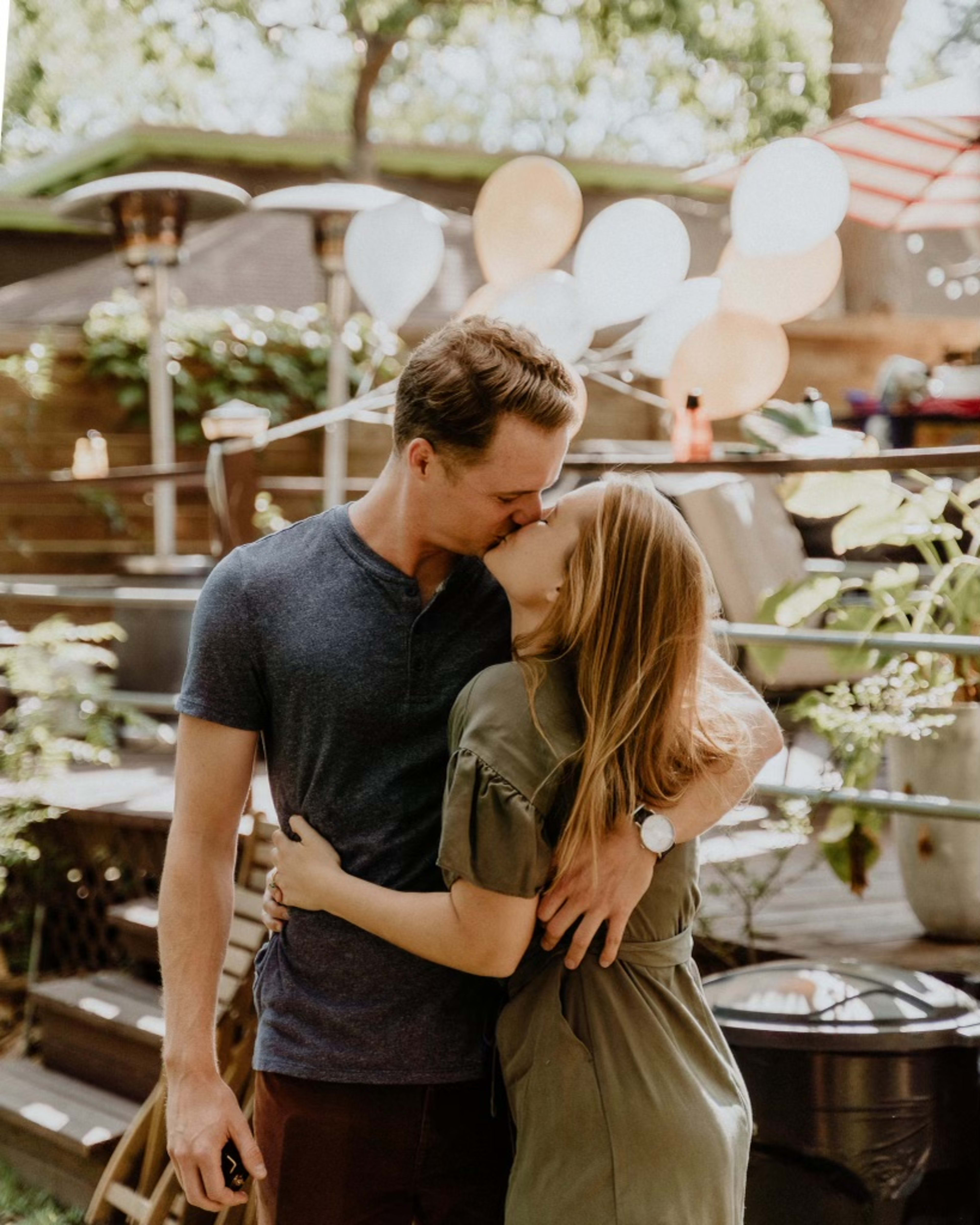 Un couple s’embrassant lors d’une fête de fiançailles en extérieur.