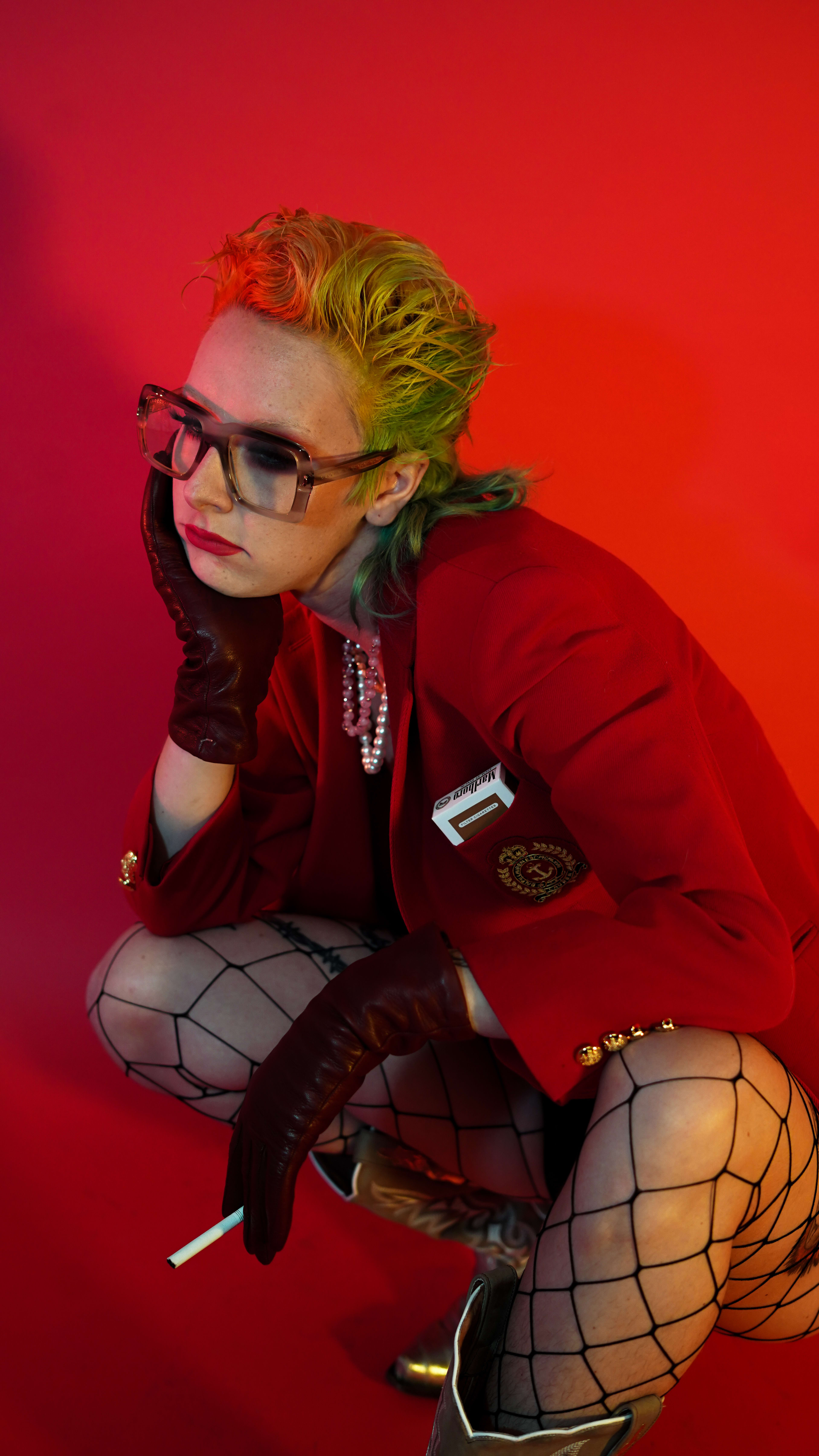 A 1980s photo shoot featuring a woman in a red jacket and fishnet stockings.