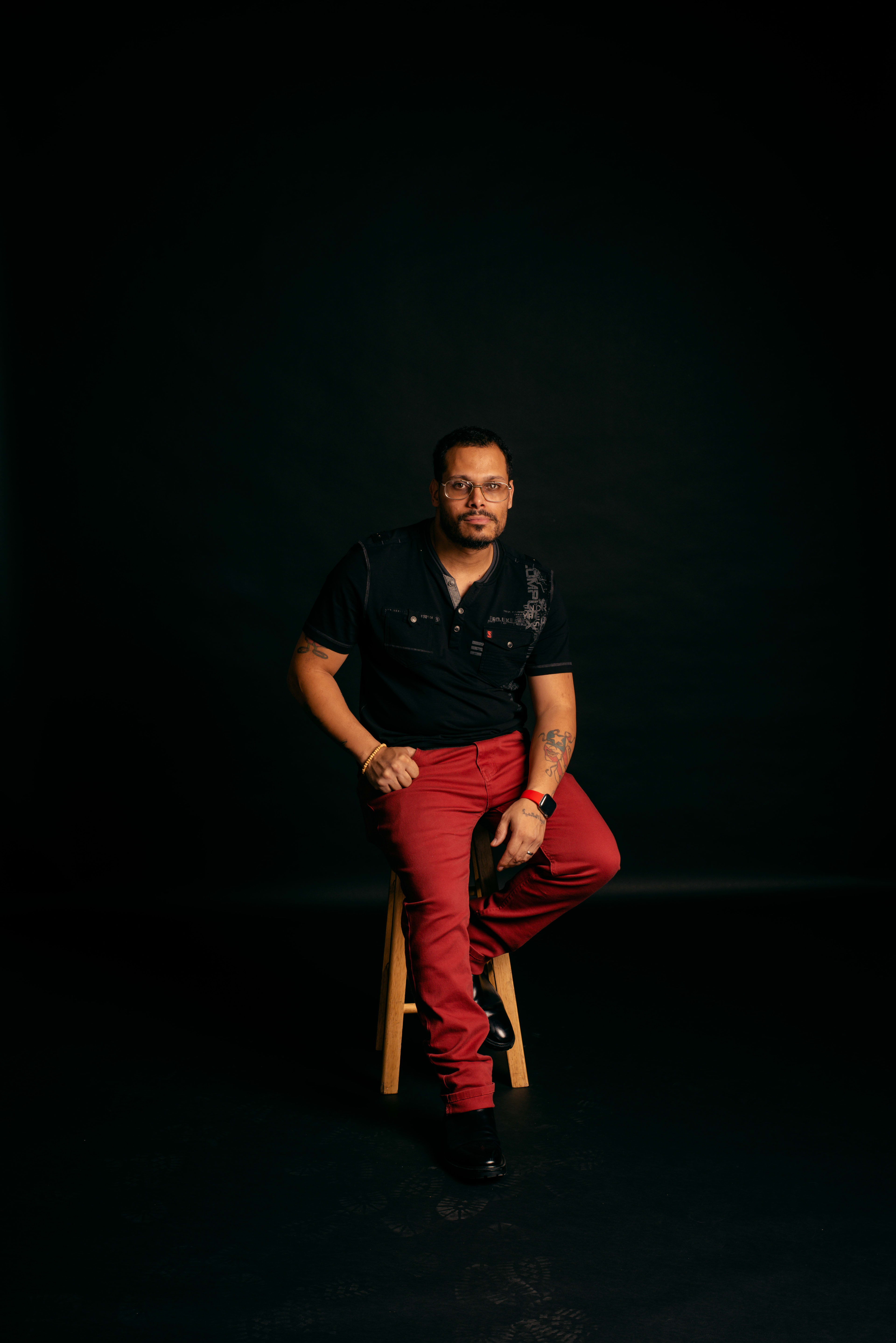 Un portrait minimaliste d'un homme assis sur une chaise dans une pièce sombre.