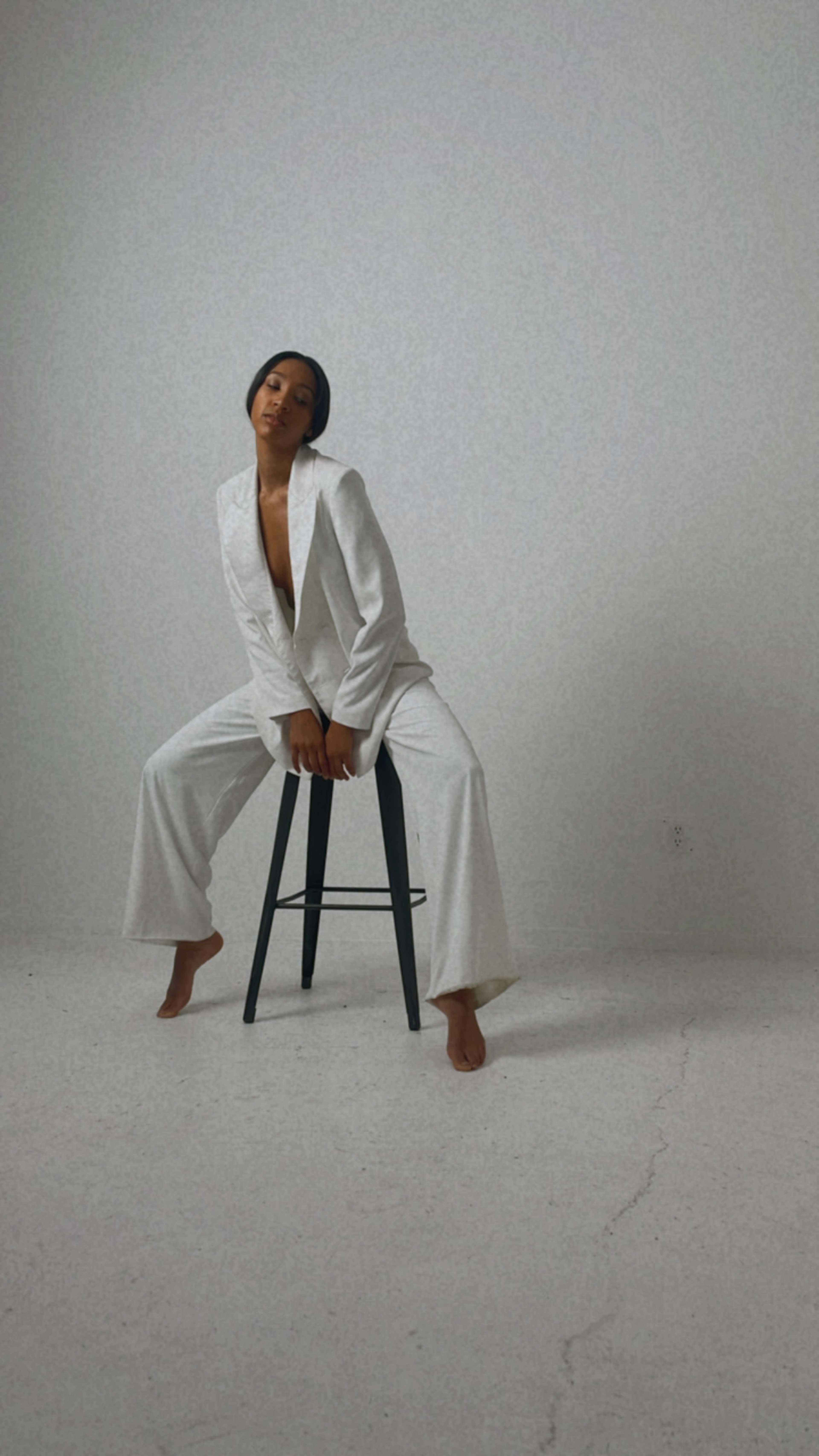 A model posing in a minimalistic, all-white fashion photo shoot.