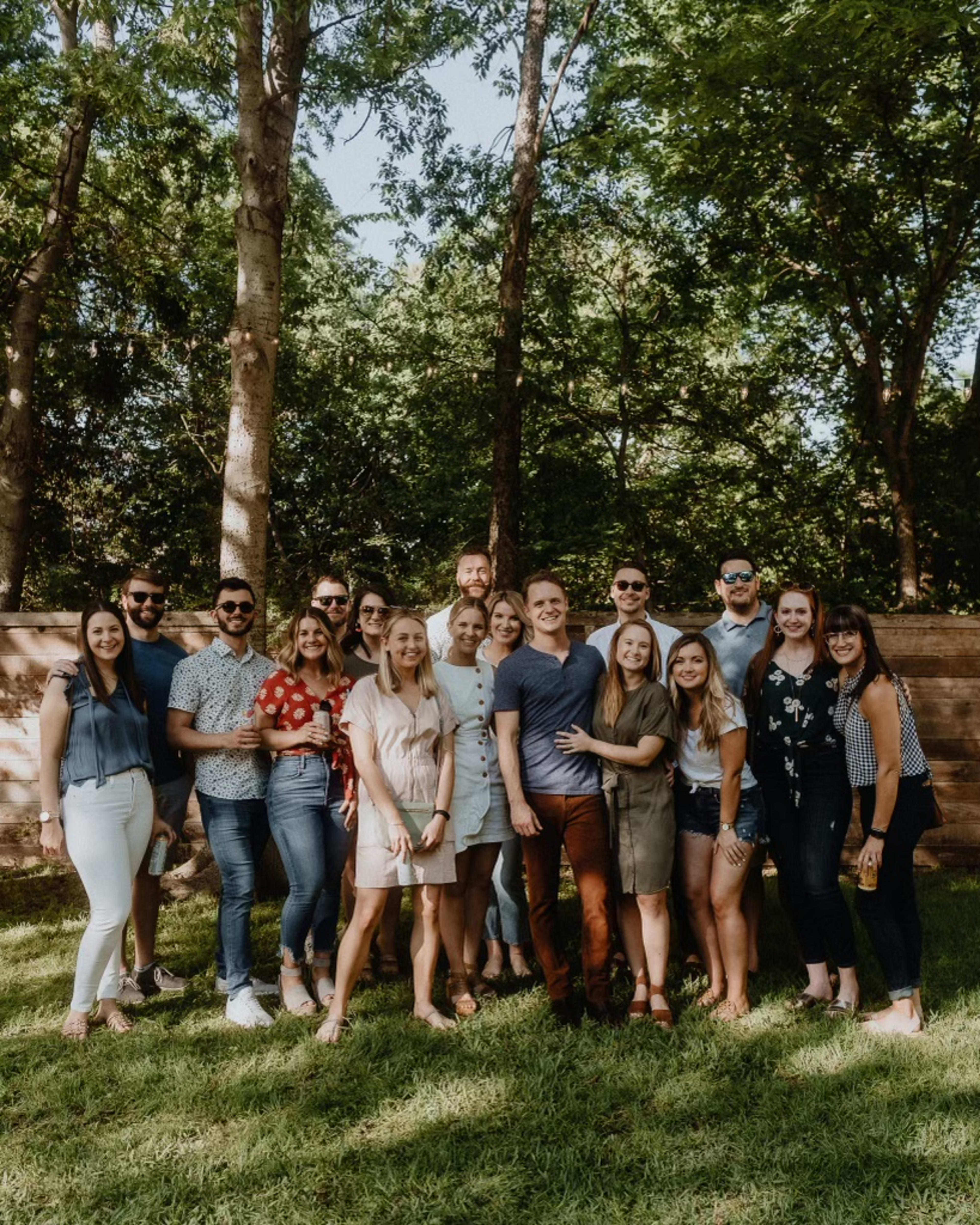 A group of people standing next to each other at an outdoor engagement party.