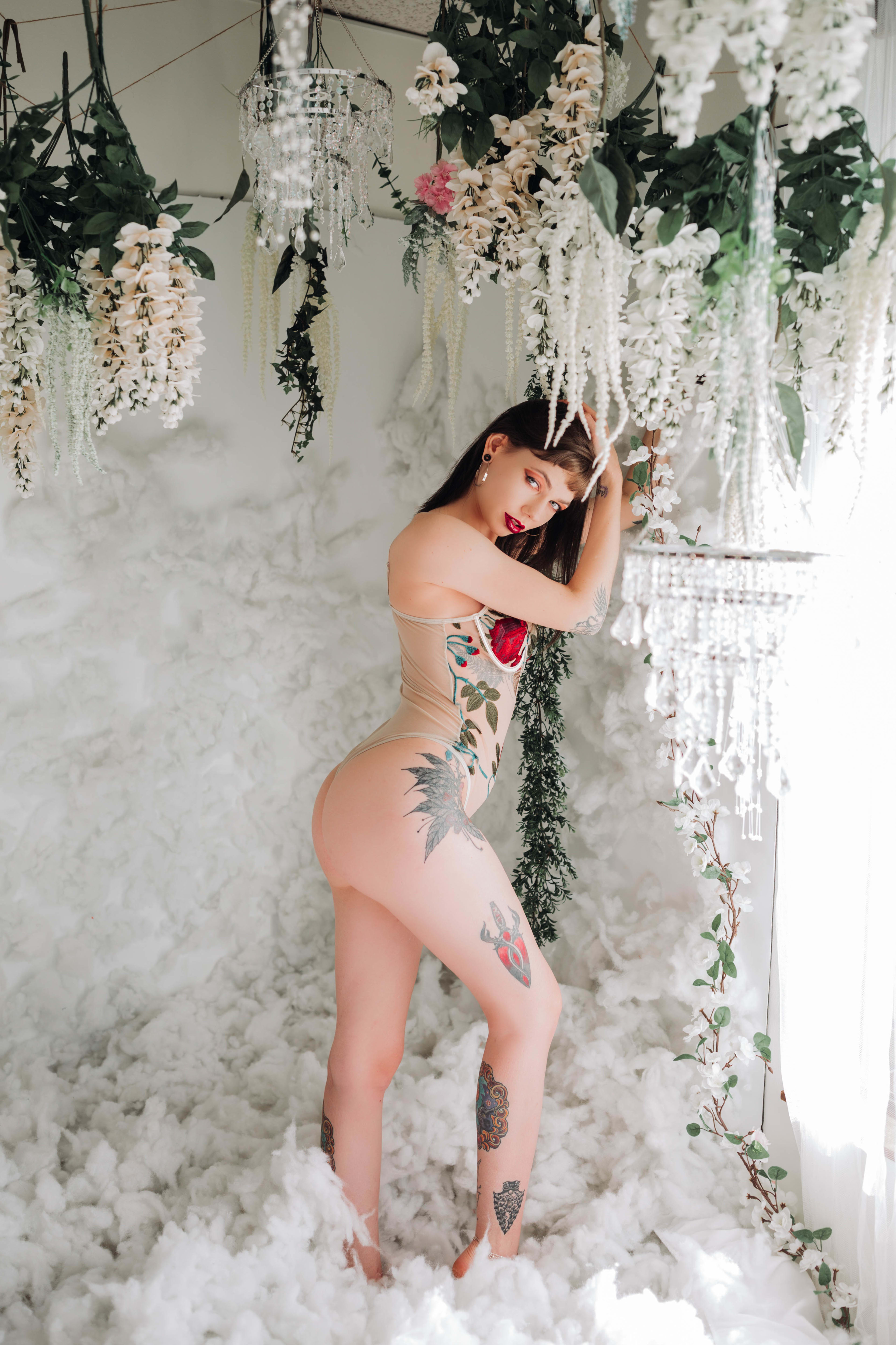 A woman with tattoos standing in a pile of cottons during a boudoir photo shoot.