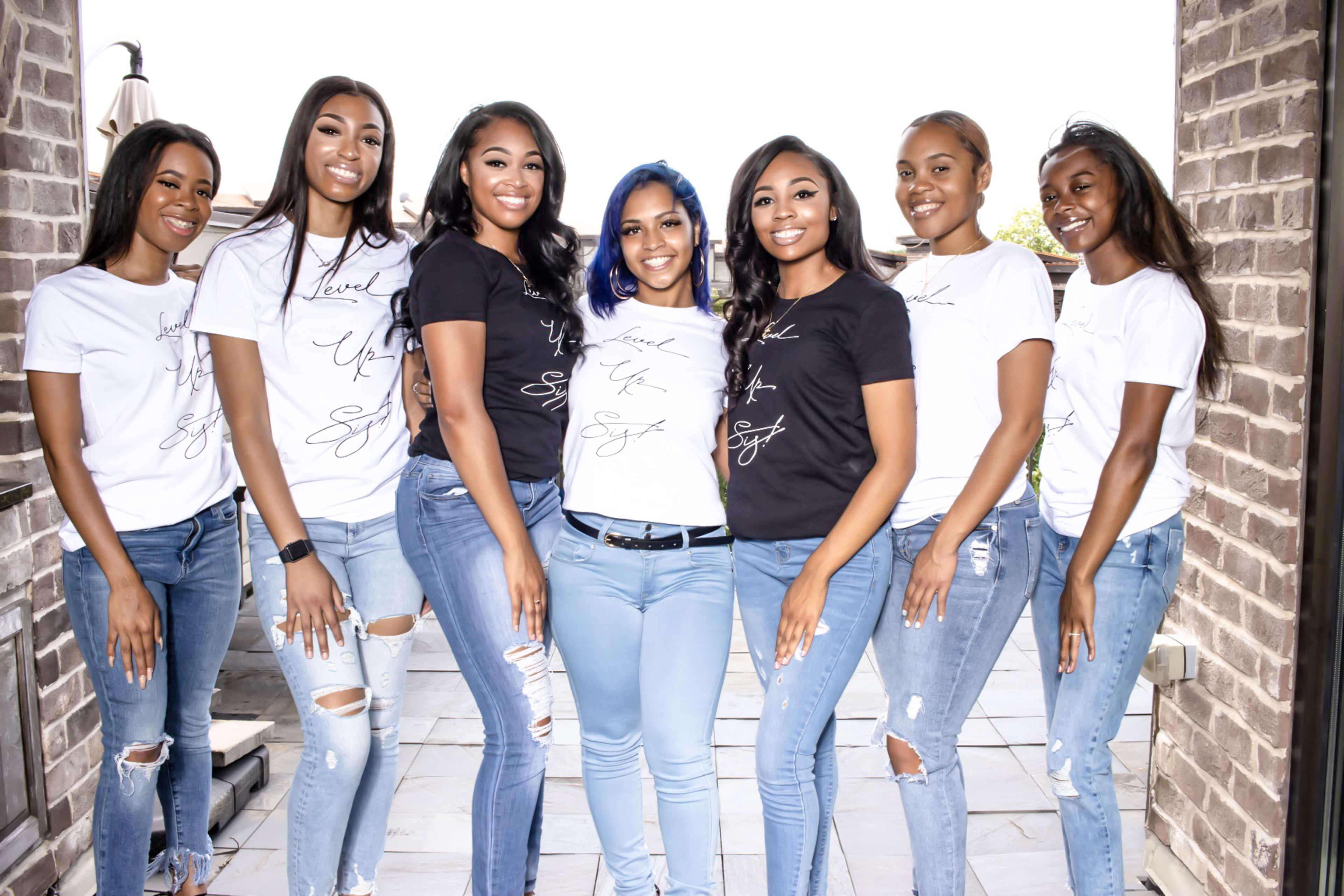 A group of women posing for an outdoor photoshoot in black and white shirts.