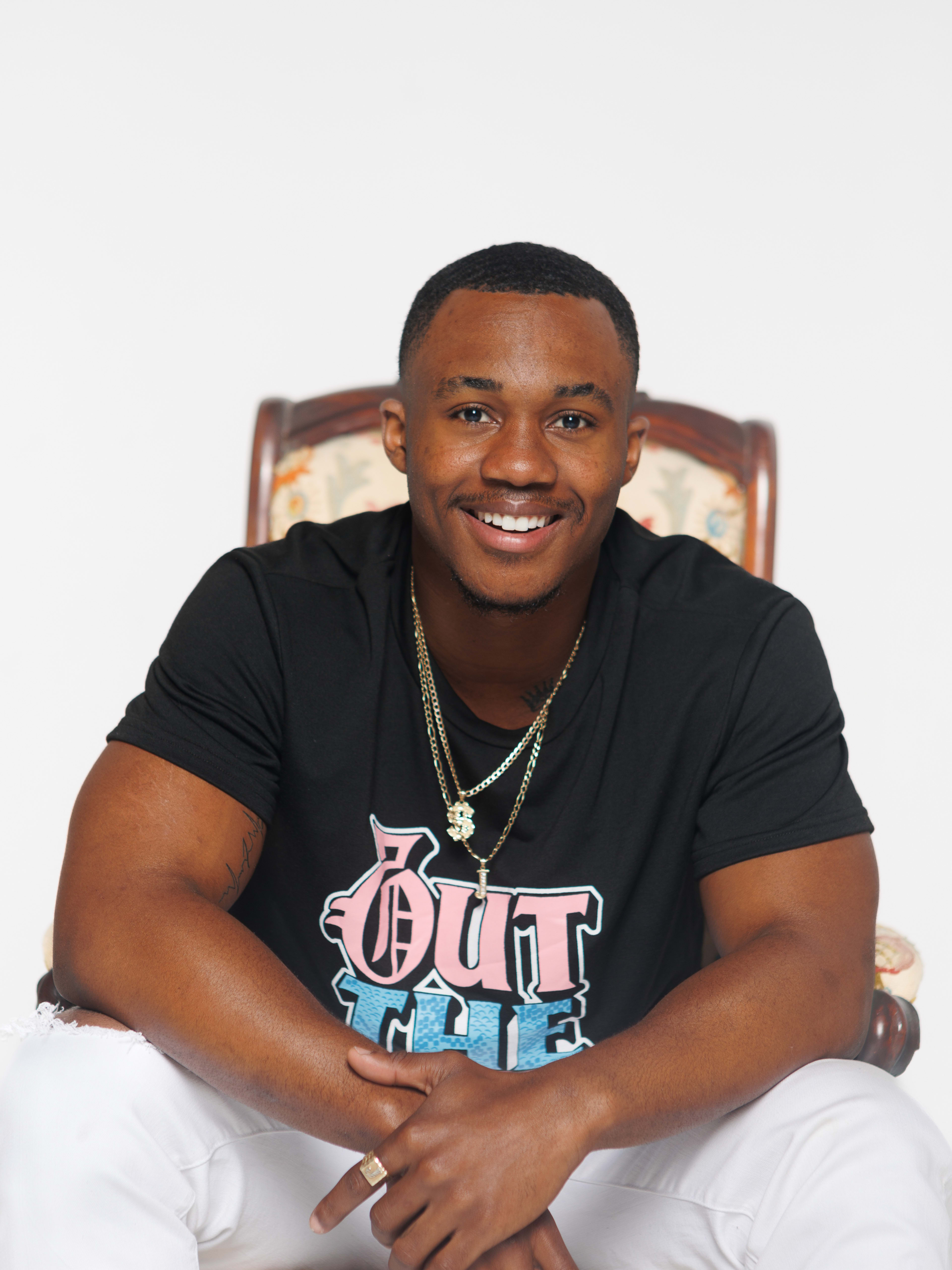 A man smiling in a chair during a photo shoot.