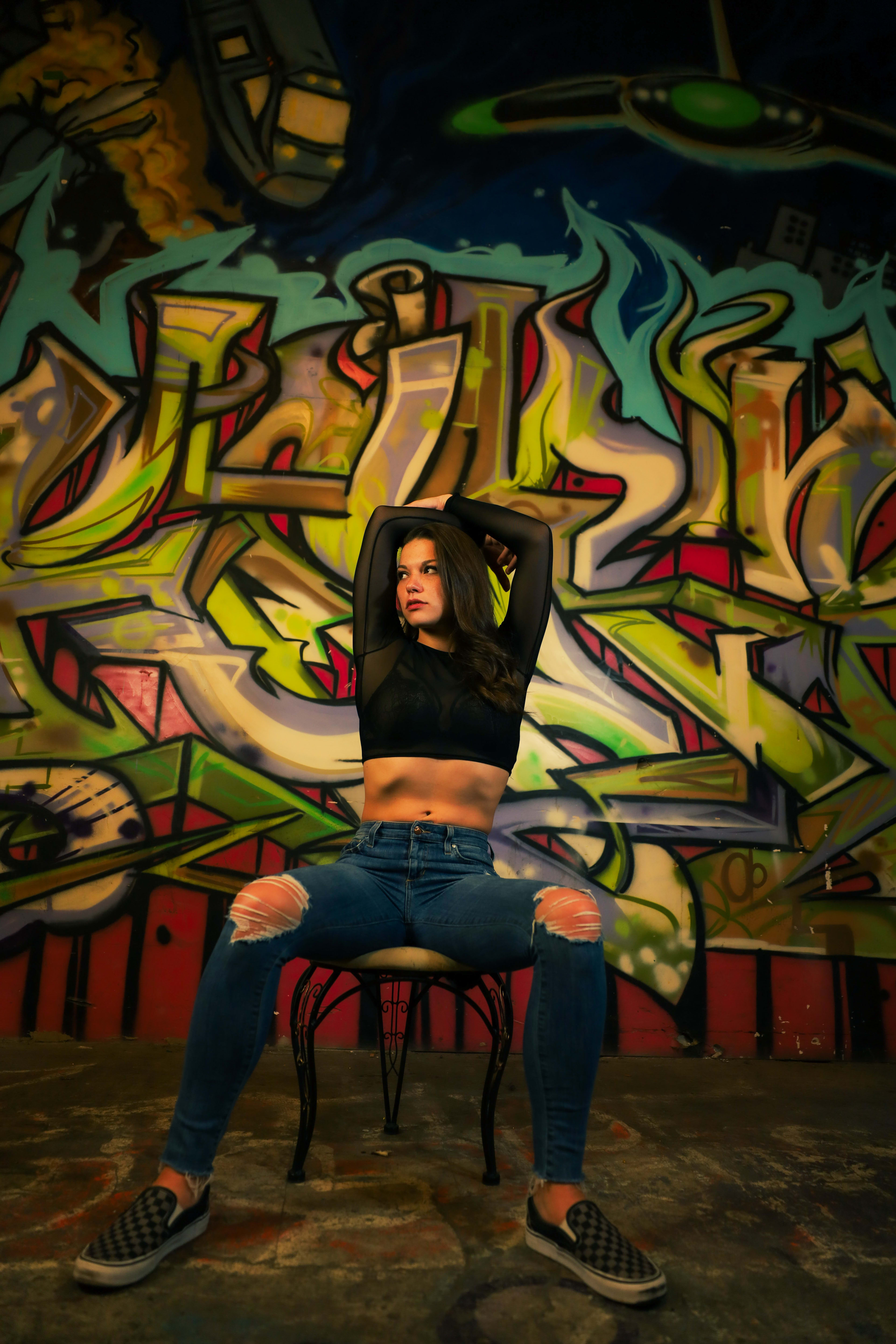 A woman posing for a photoshoot in front of a graffiti-covered wall.