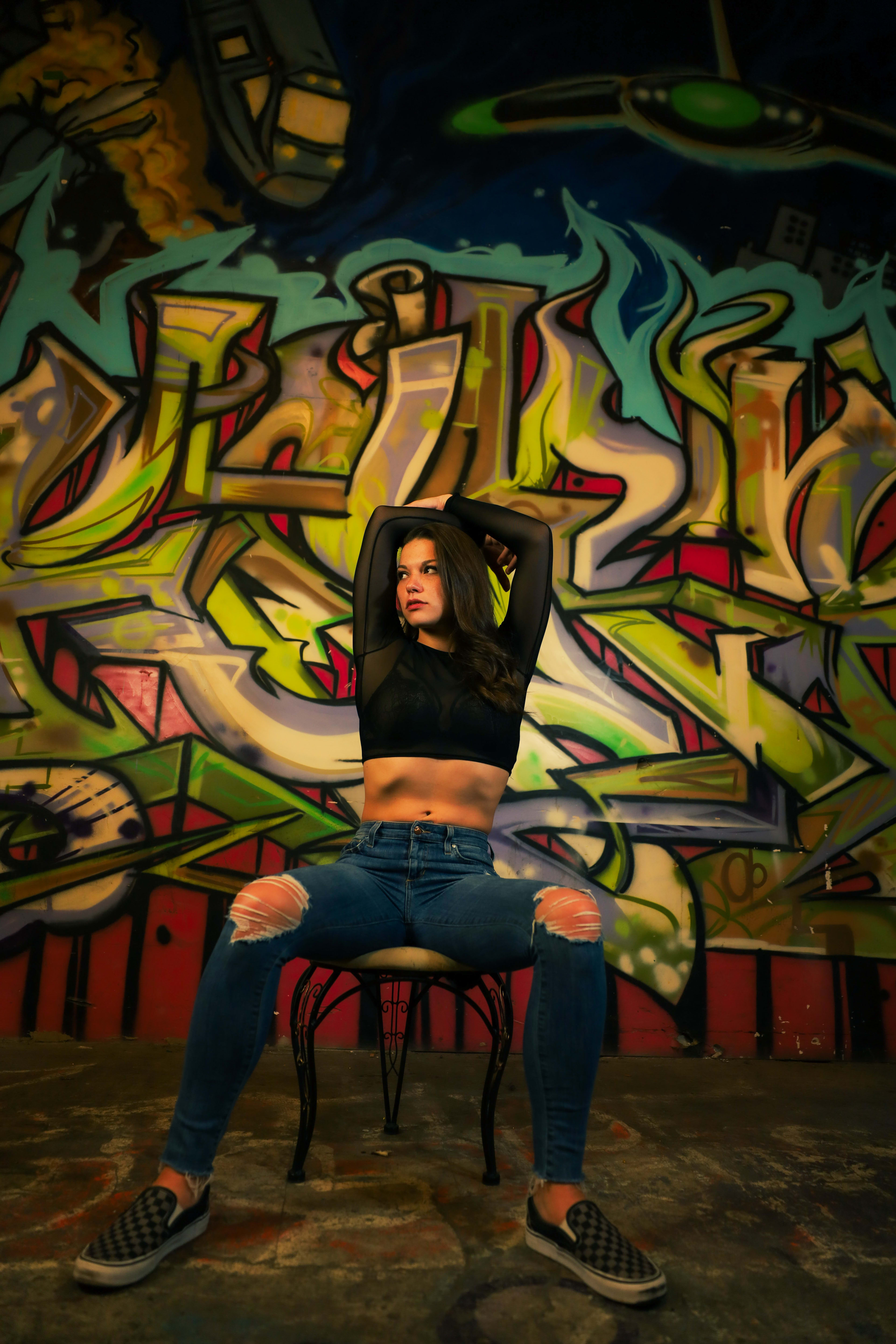 A woman posing for a photo shoot in front of a graffiti-covered wall.