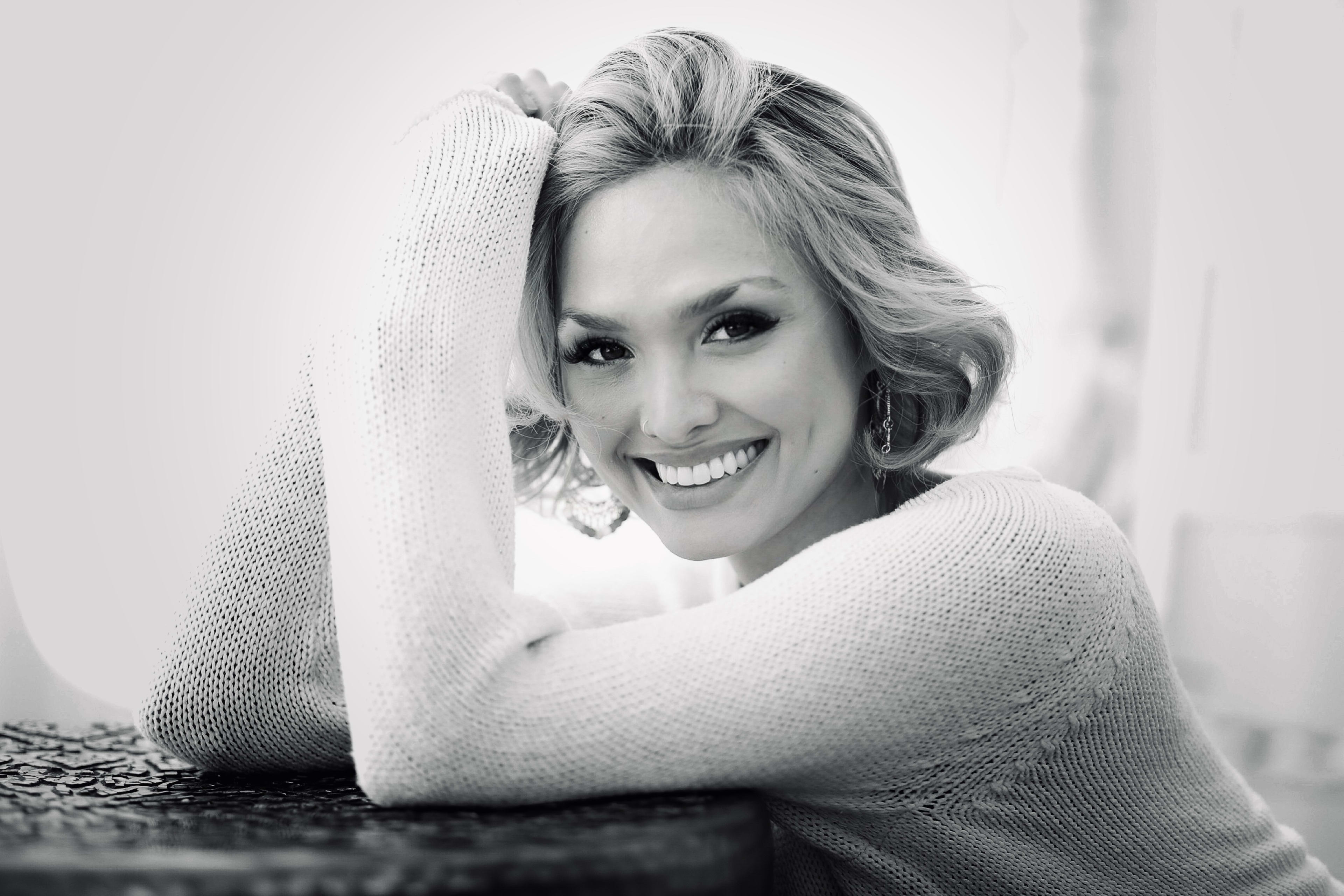 A black and white portrait of a smiling woman.