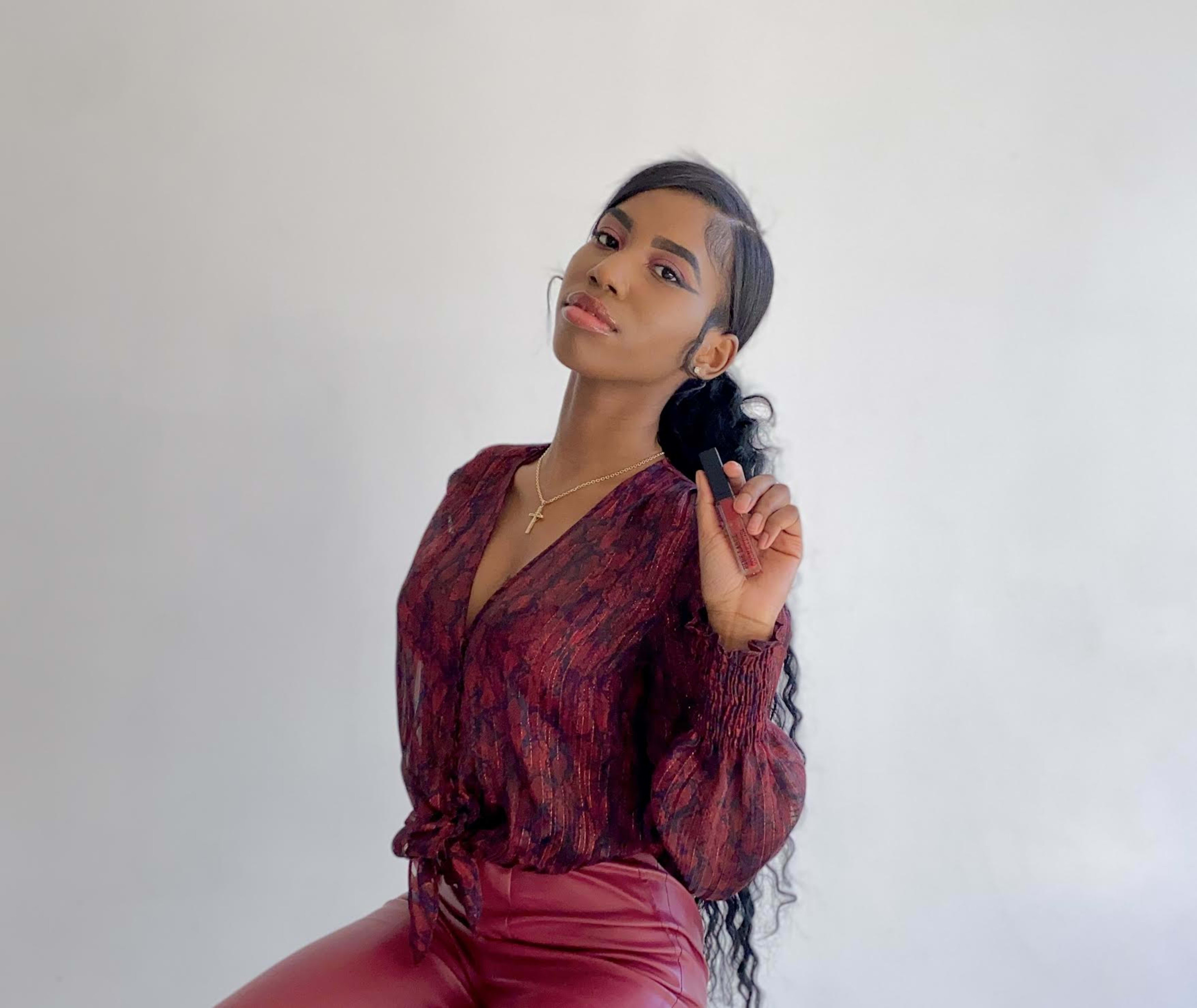 A woman in a red top is styling hair for a photoshoot.