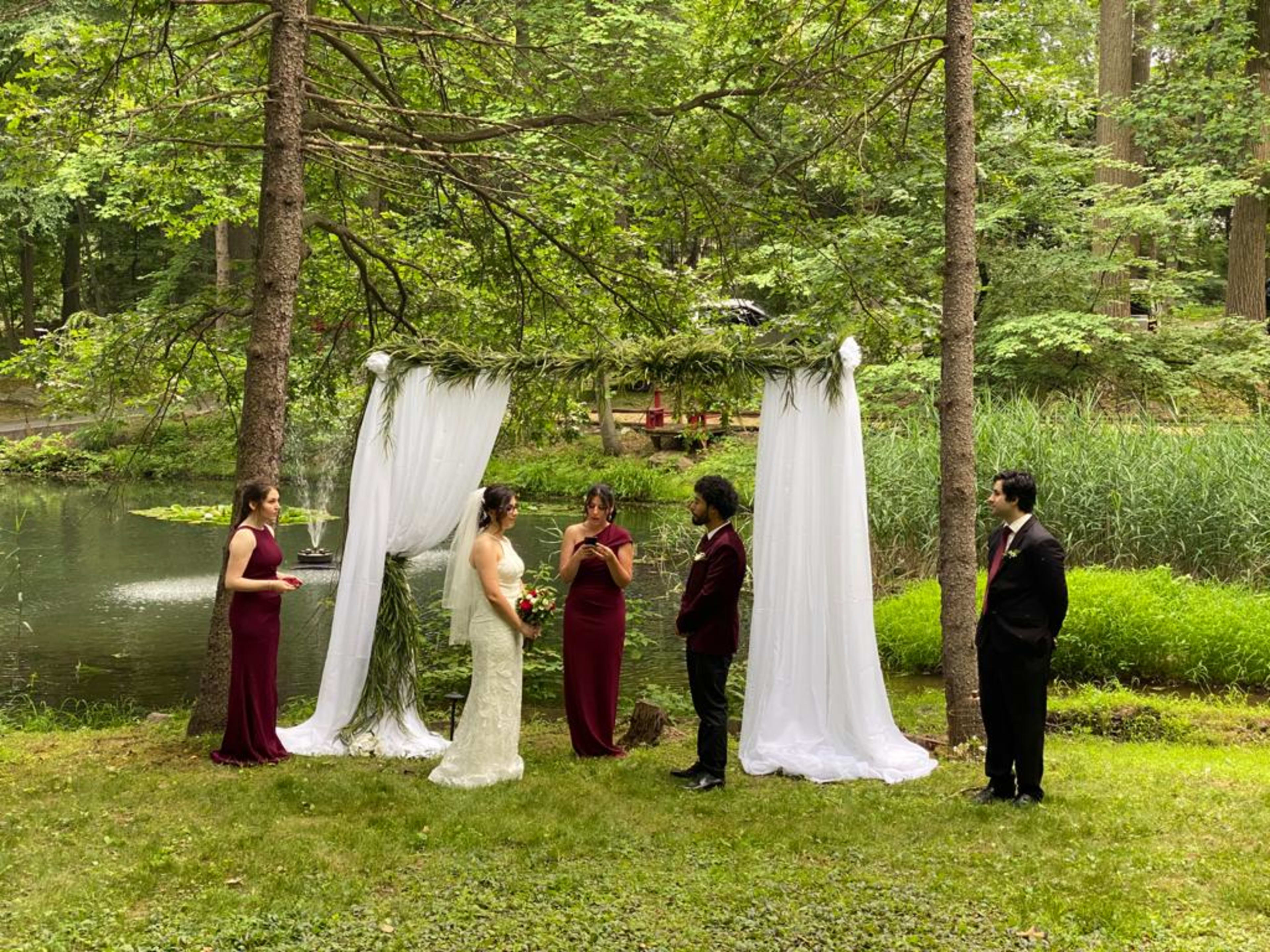 A couple getting married outdoors on green grass by a lake.