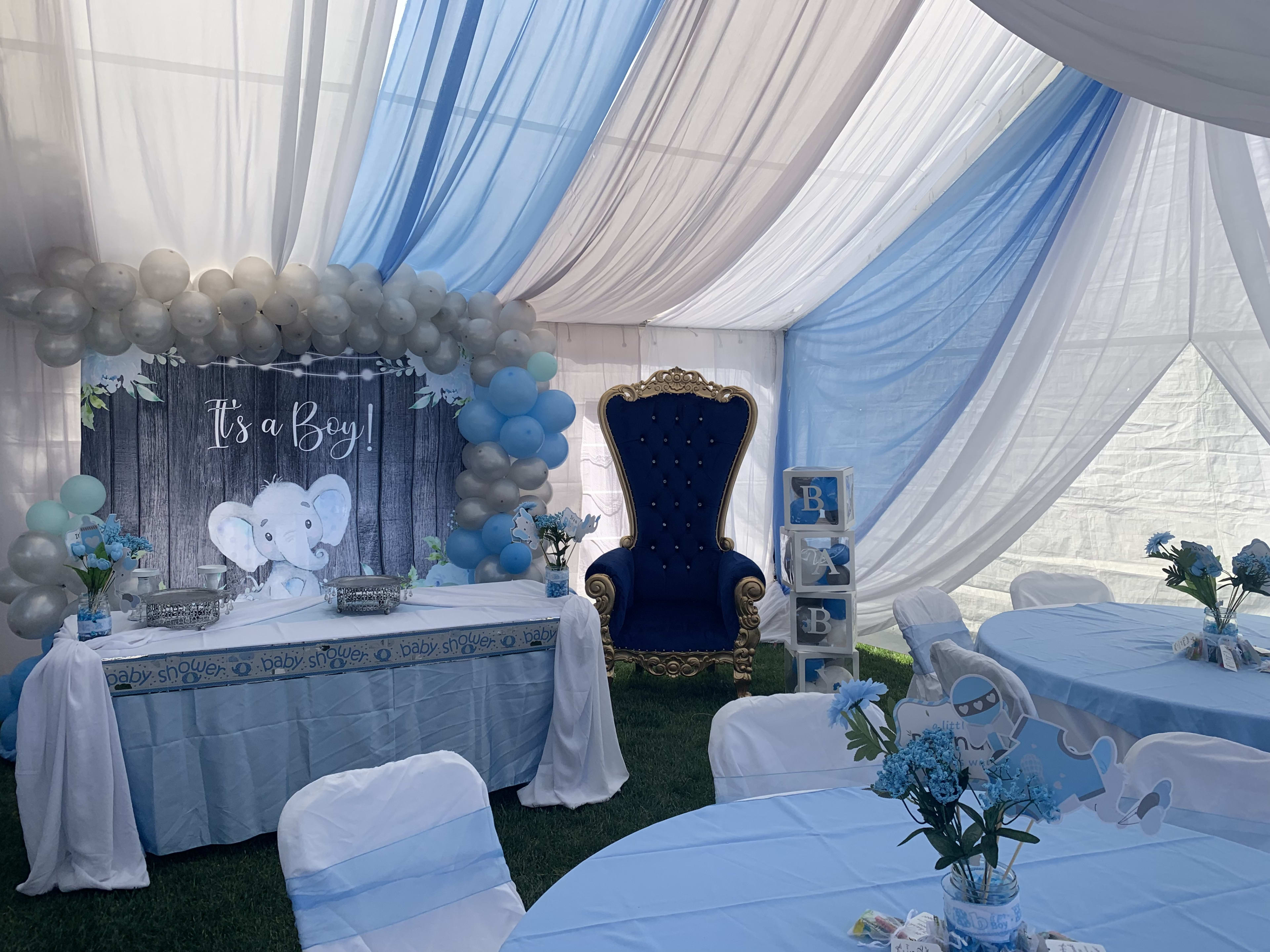 A blue and white baby shower setup with elephant balloons.