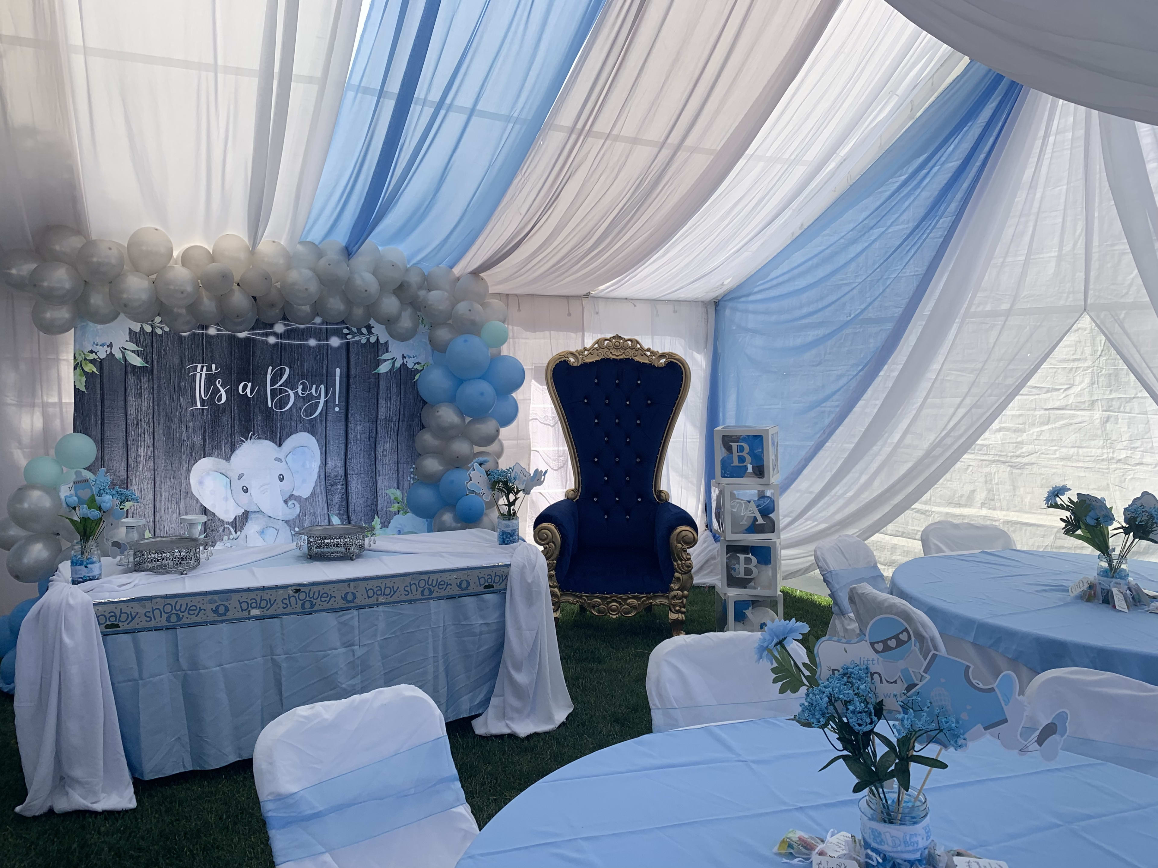 Un decorado de baby shower azul y blanco con globos de elefantes.