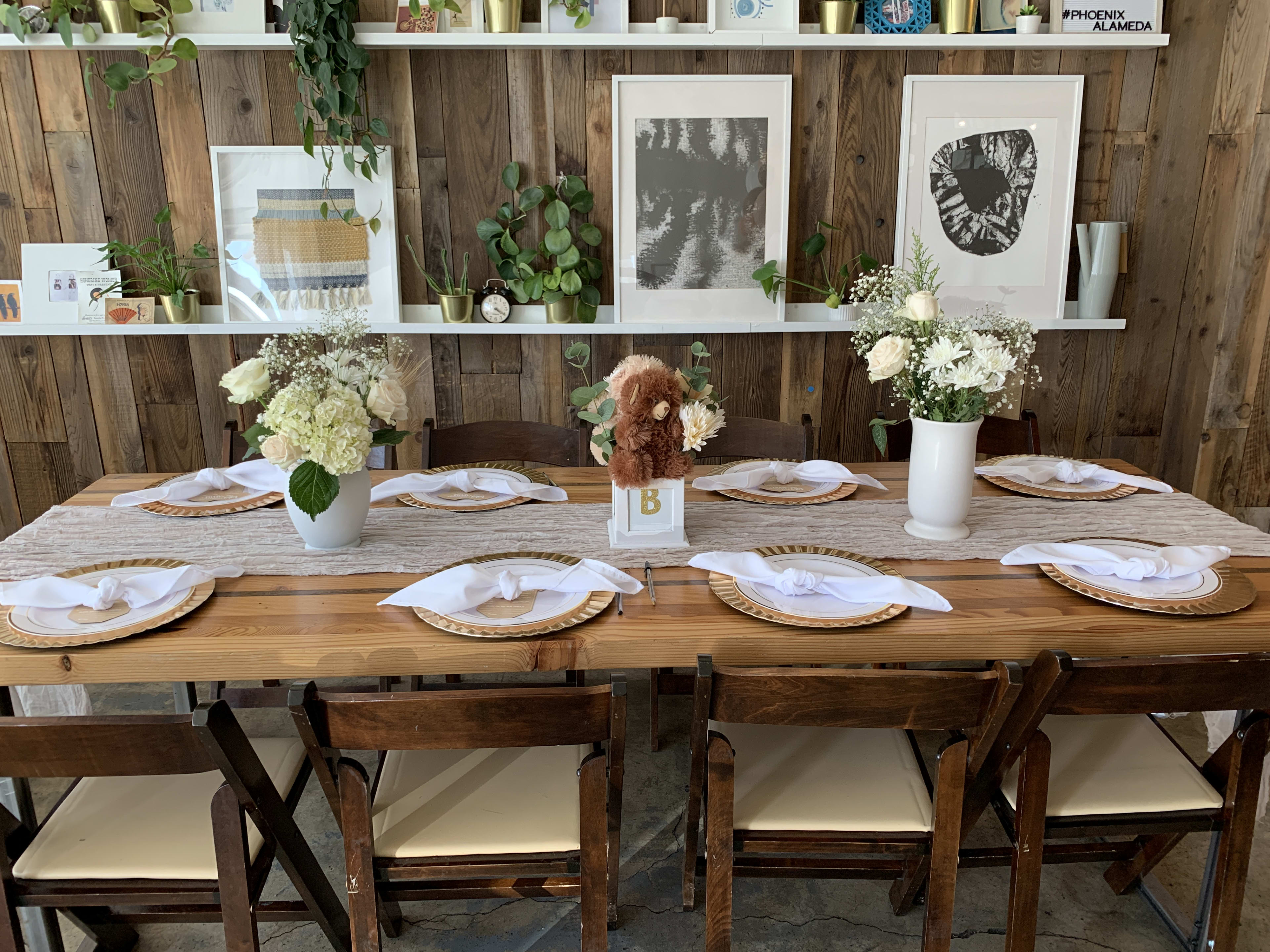 A rustic wooden table adorned with vases of flowers for a gender-neutral baby shower brunch.
