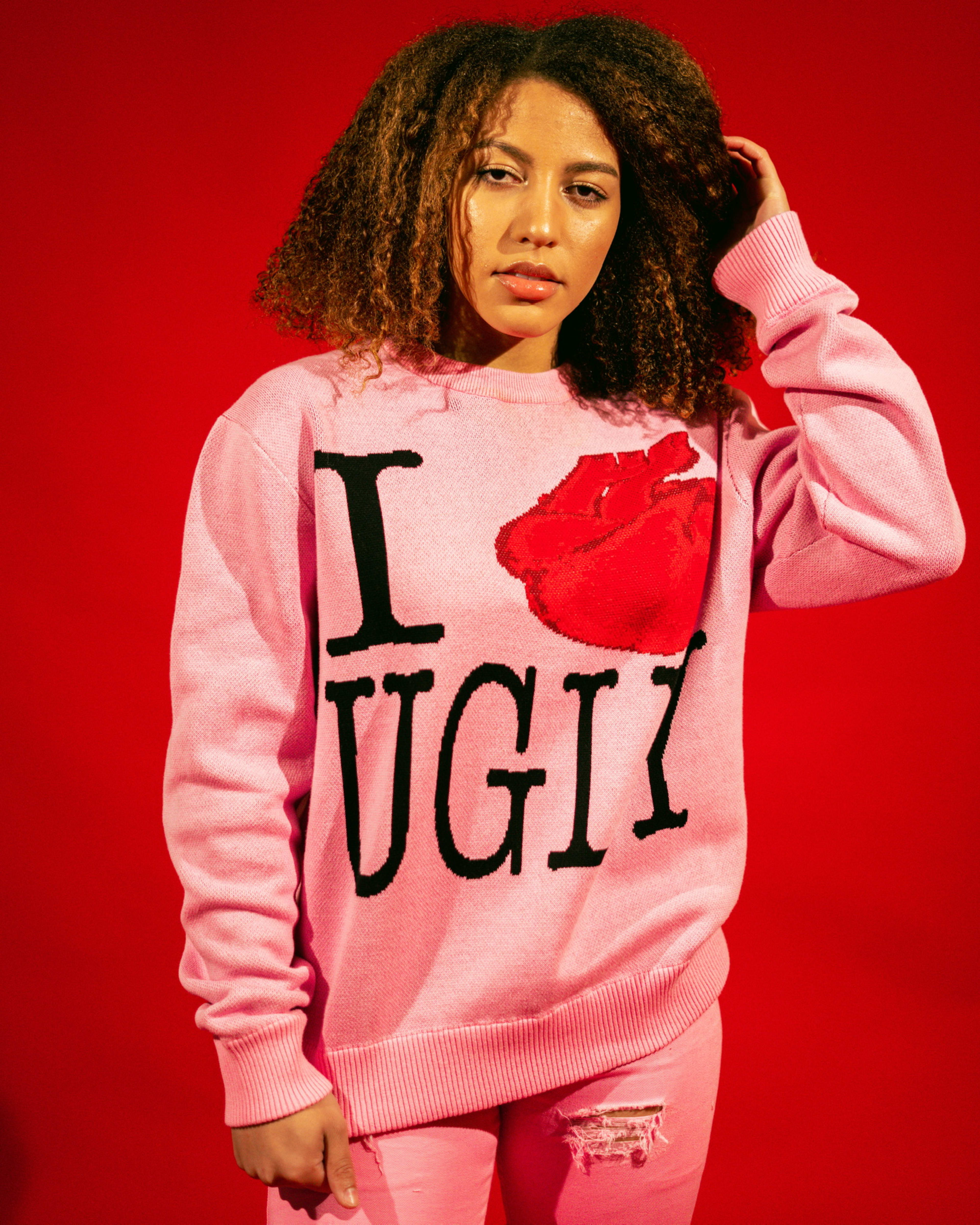 A fashion model sporting a pink sweater with a red heart for a photoshoot.