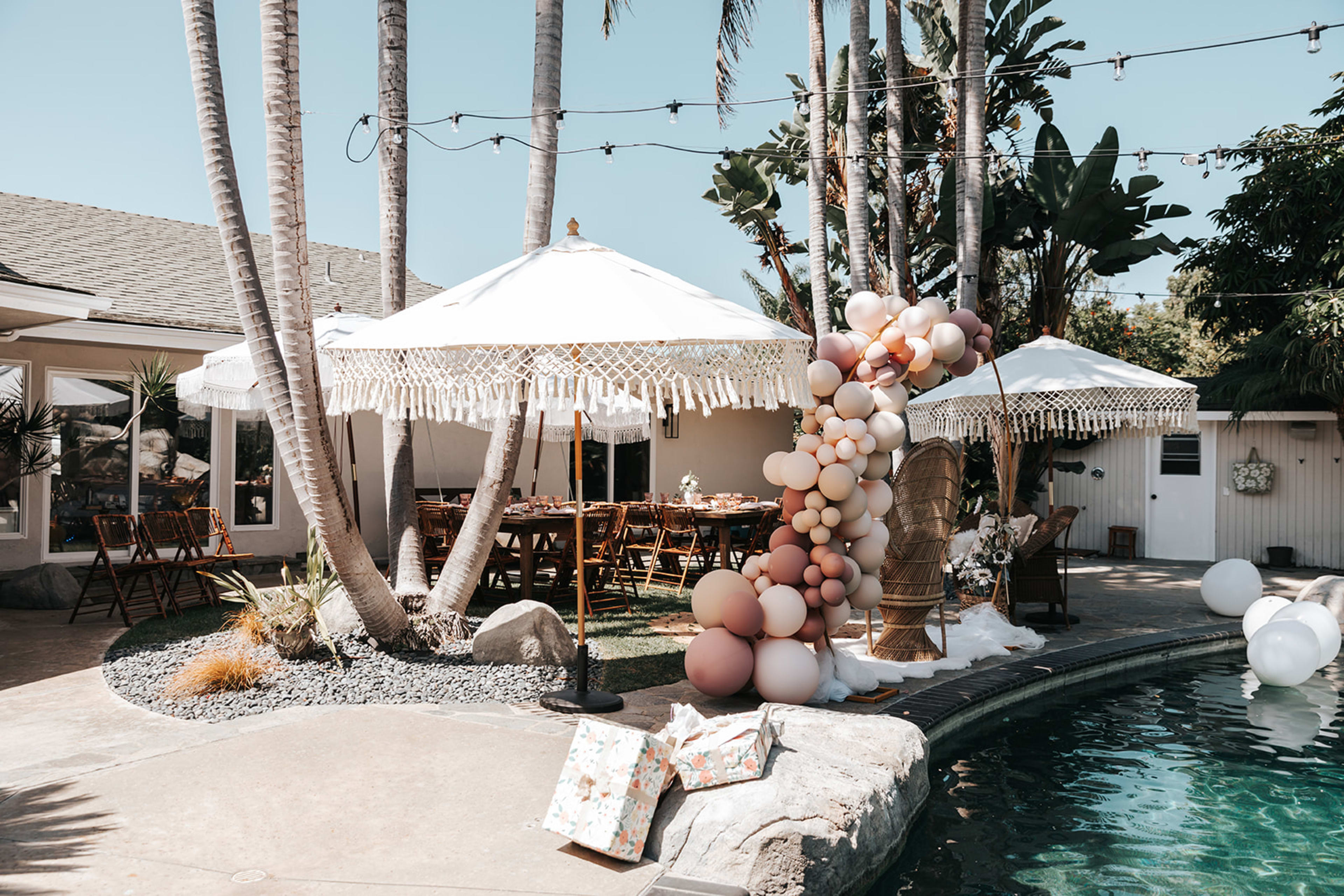 Una piscina al aire libre de estilo boho adornada con globos, perfecta para una despedida de soltera.