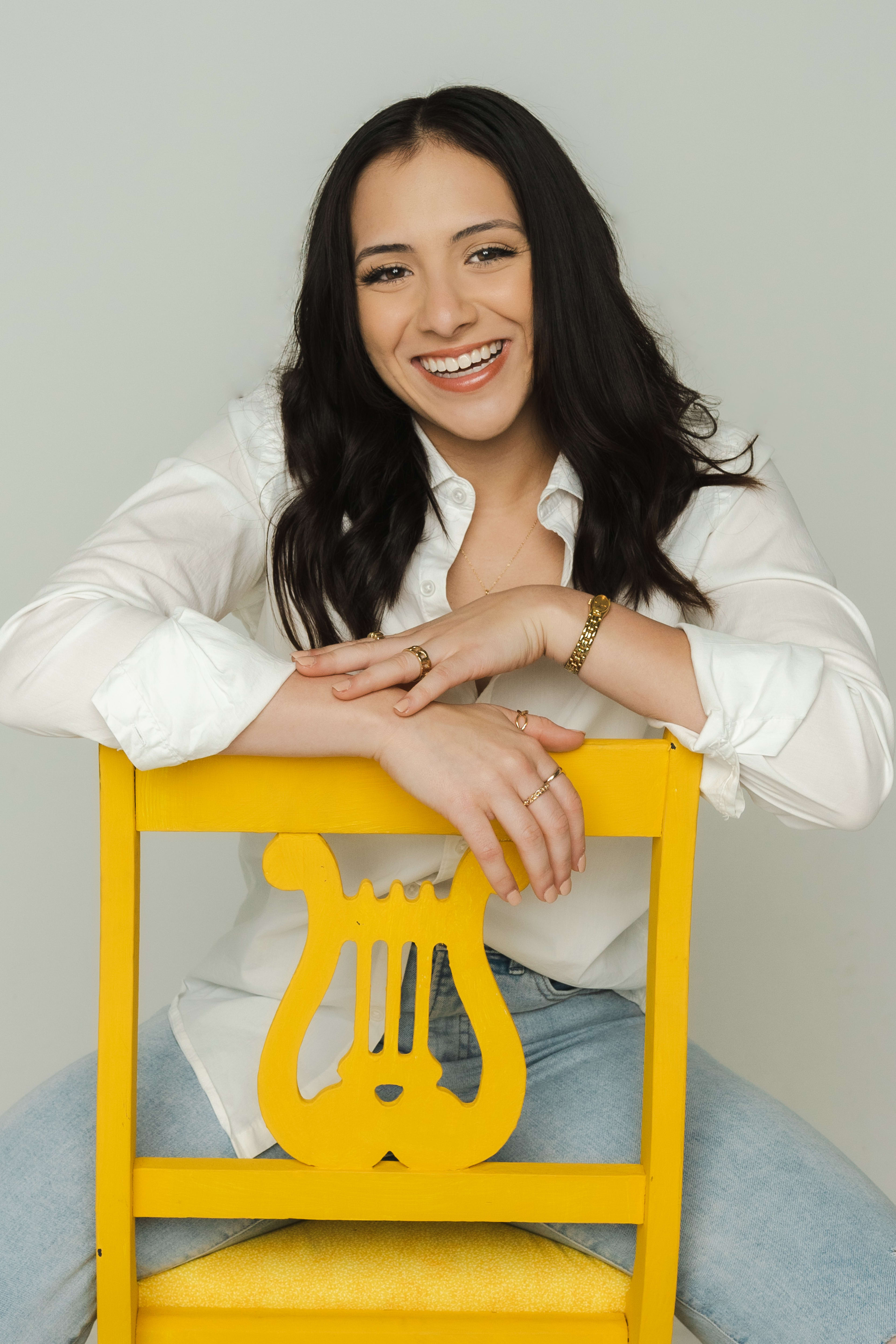 A portrait of a woman sitting on top of a yellow chair.