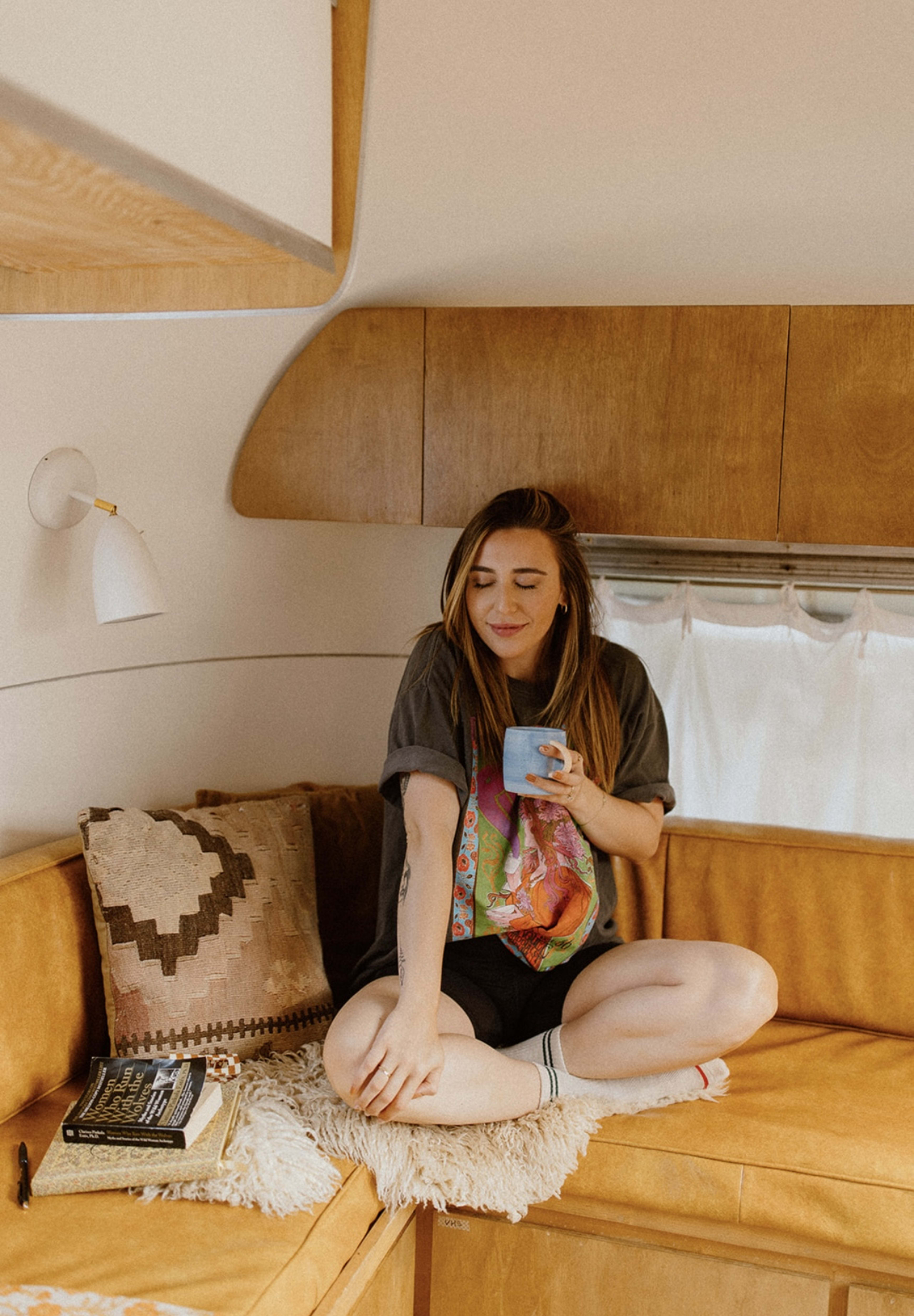 A woman holding a cup on a brown retro couch.