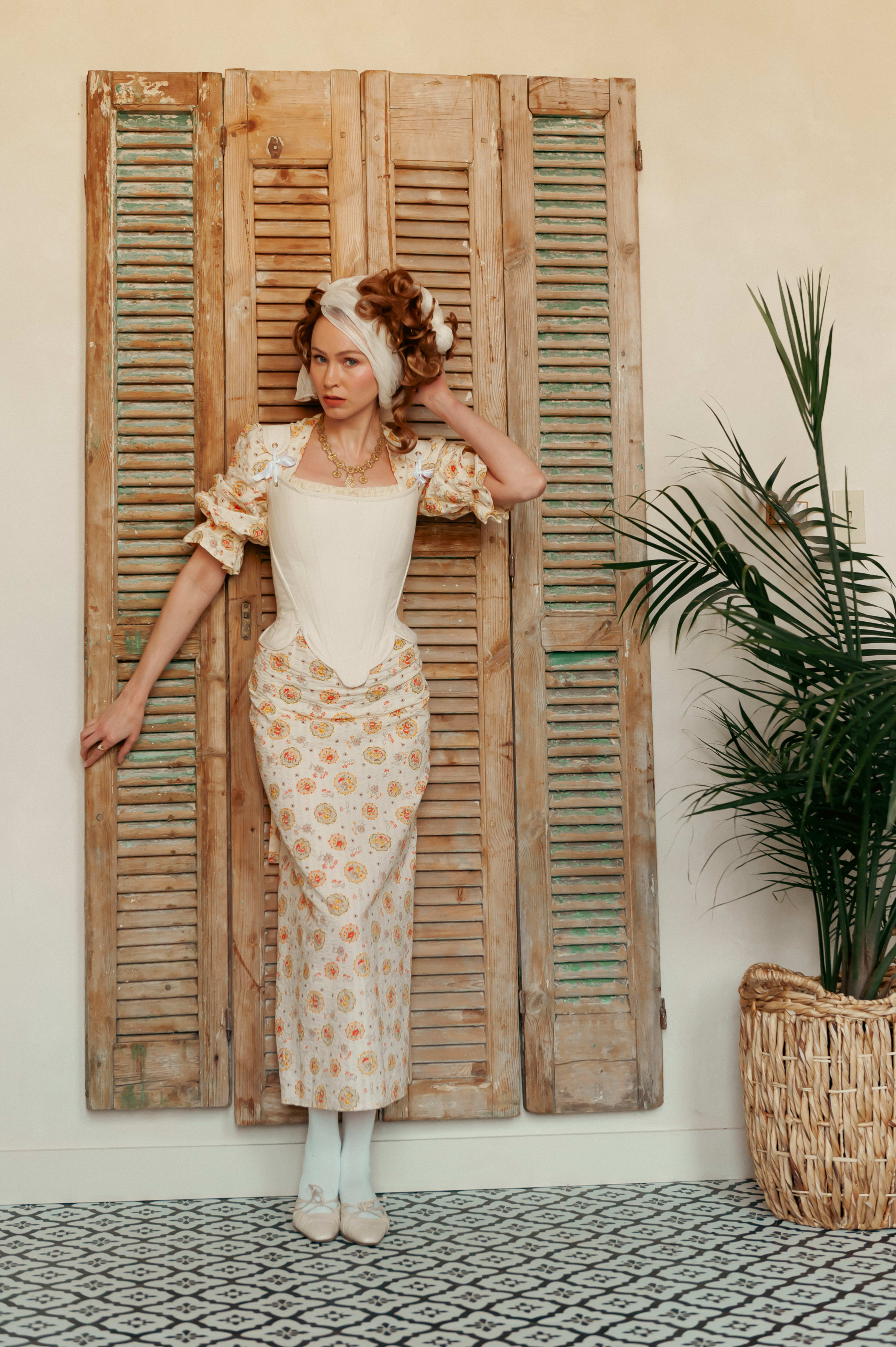 A rustic photo shoot of a woman standing in front of a wooden door.