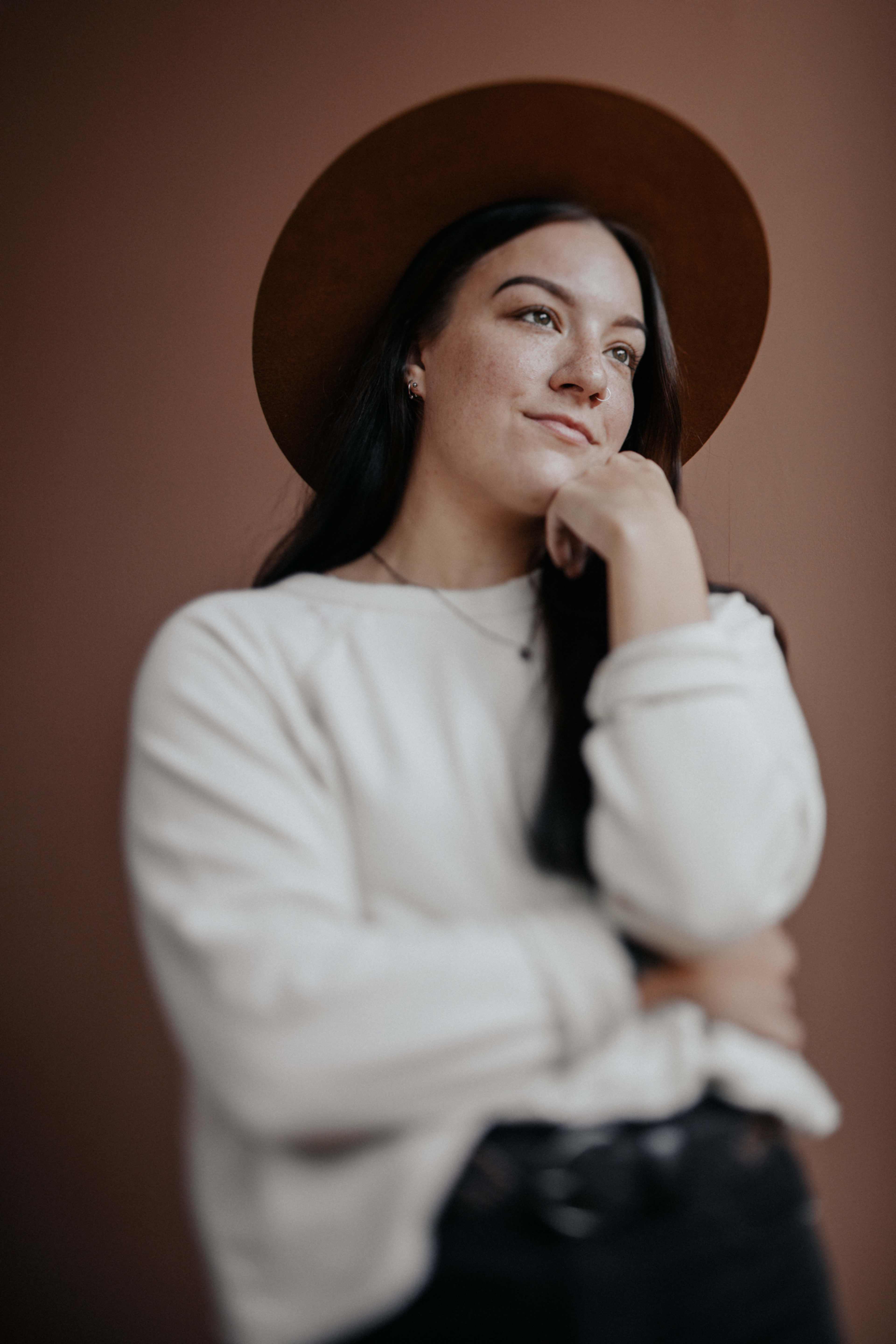 A woman wearing a hat poses for a minimal head shot portrait.