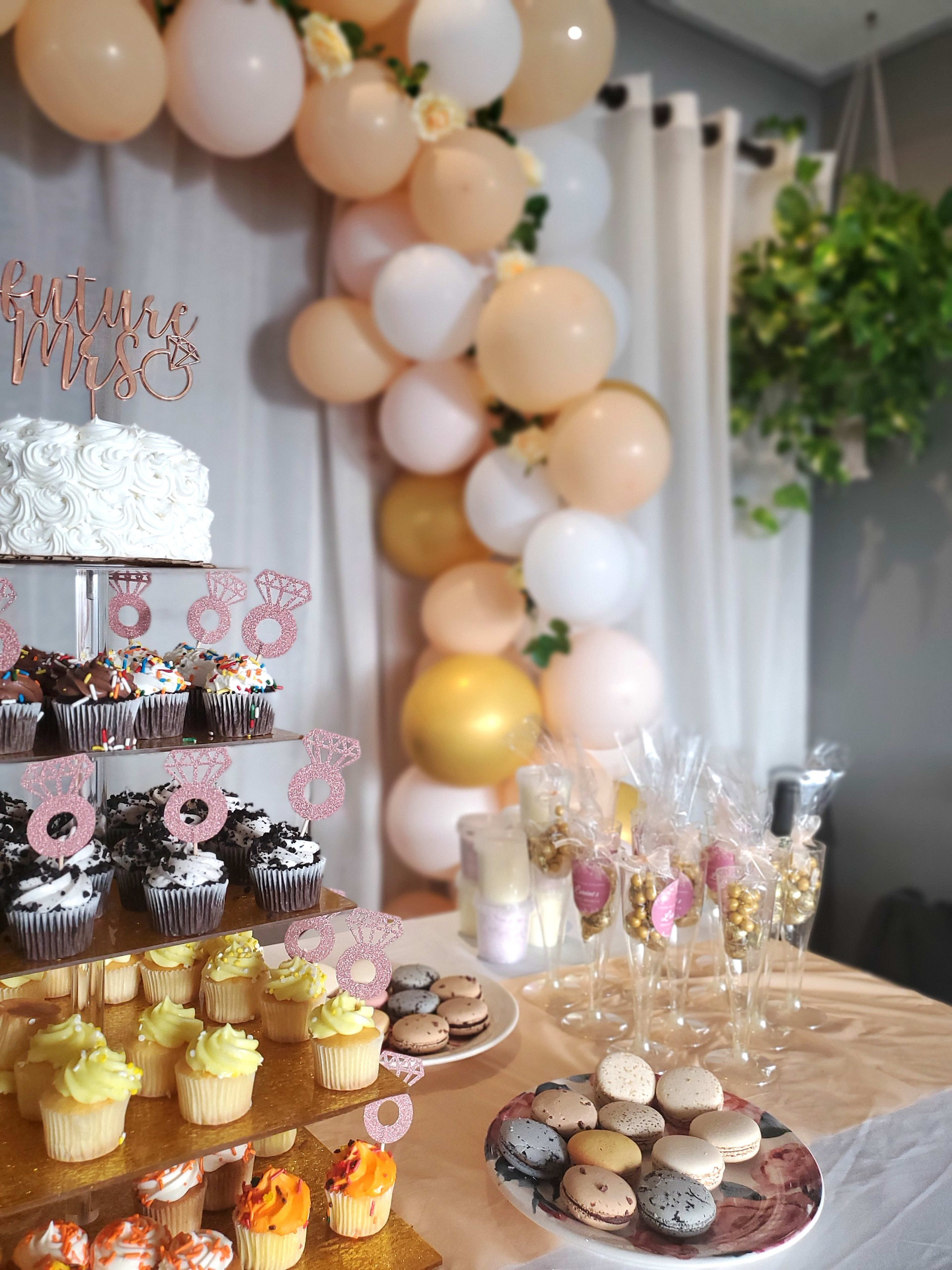 Una mesa de despedida de soltera adornada con muchos cupcakes y aperitivos coloridos.
