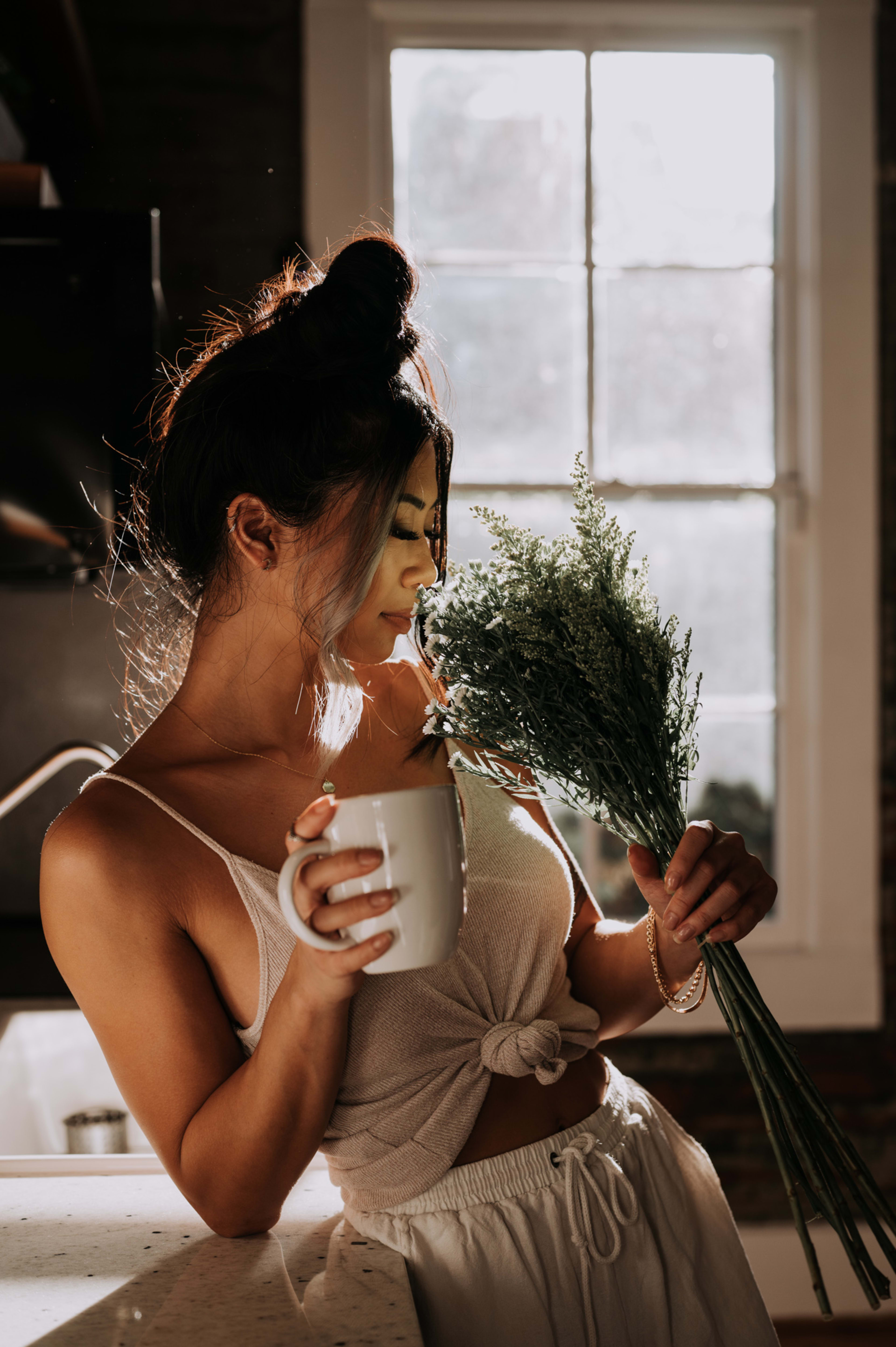 Ein Fotoshooting mit einer Frau, die eine Tasse Kaffee und Blumen in der Hand hält.