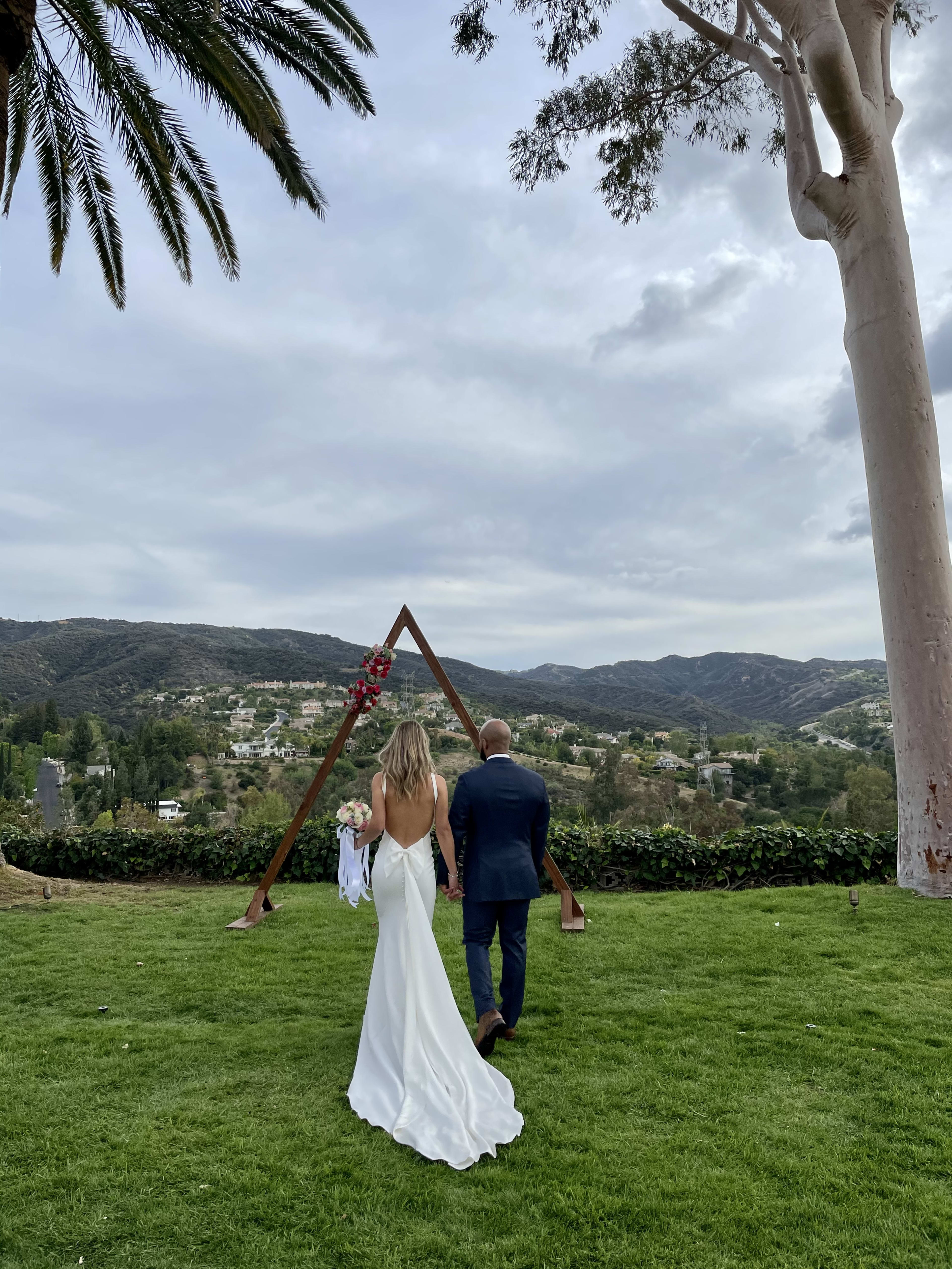 A bride and groom walking on the grass.