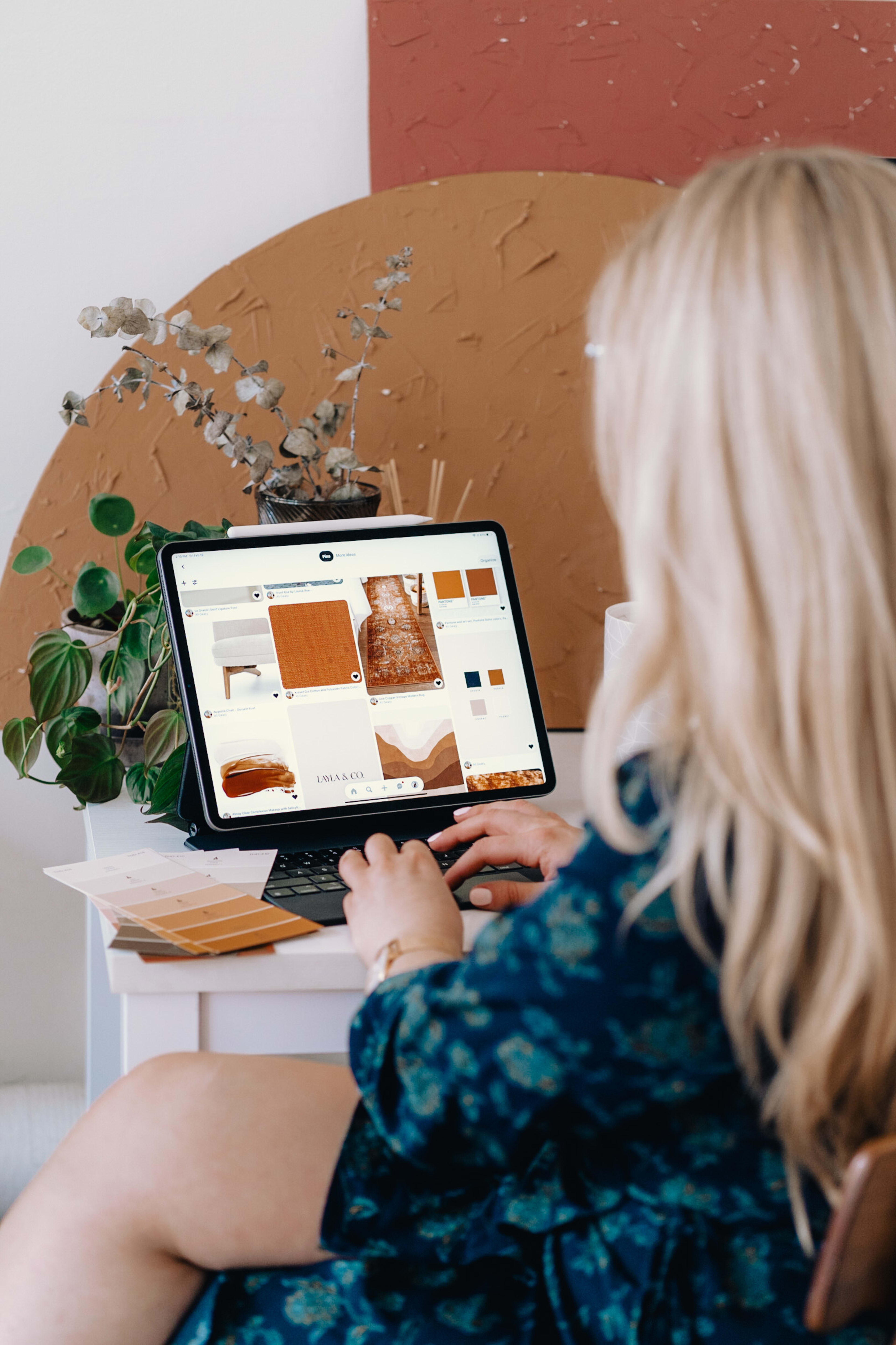 Une femme travaillant sur son ordinateur portable devant une plante.