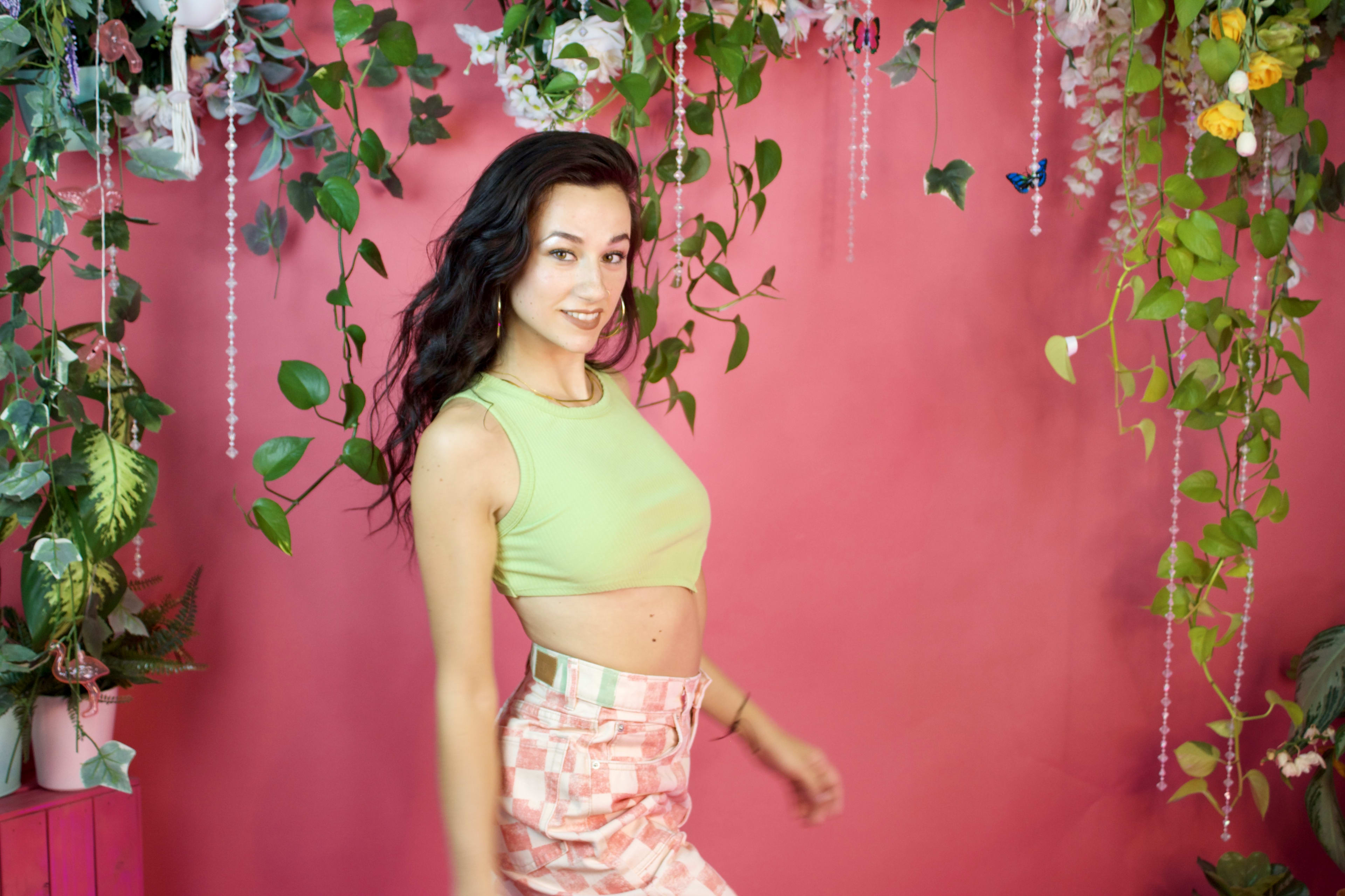 A woman posing in front of a pink wall for a fashion photo shoot.