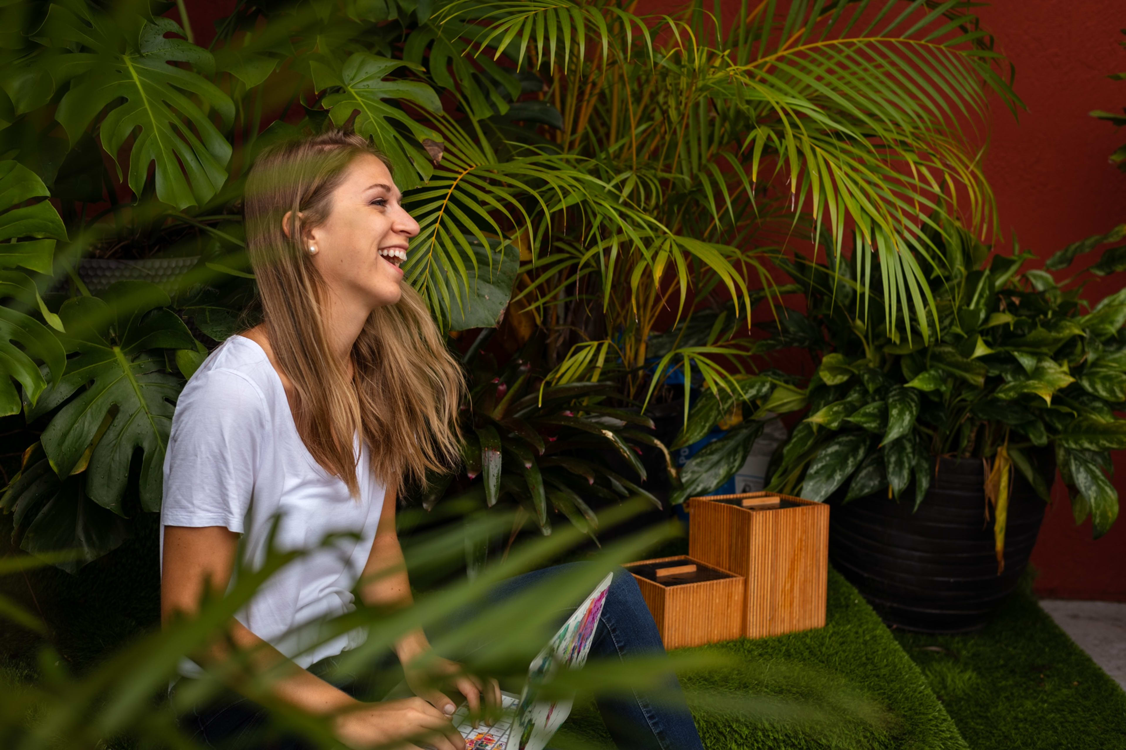 A woman posing for a photo shoot in front of green outdoor plants.