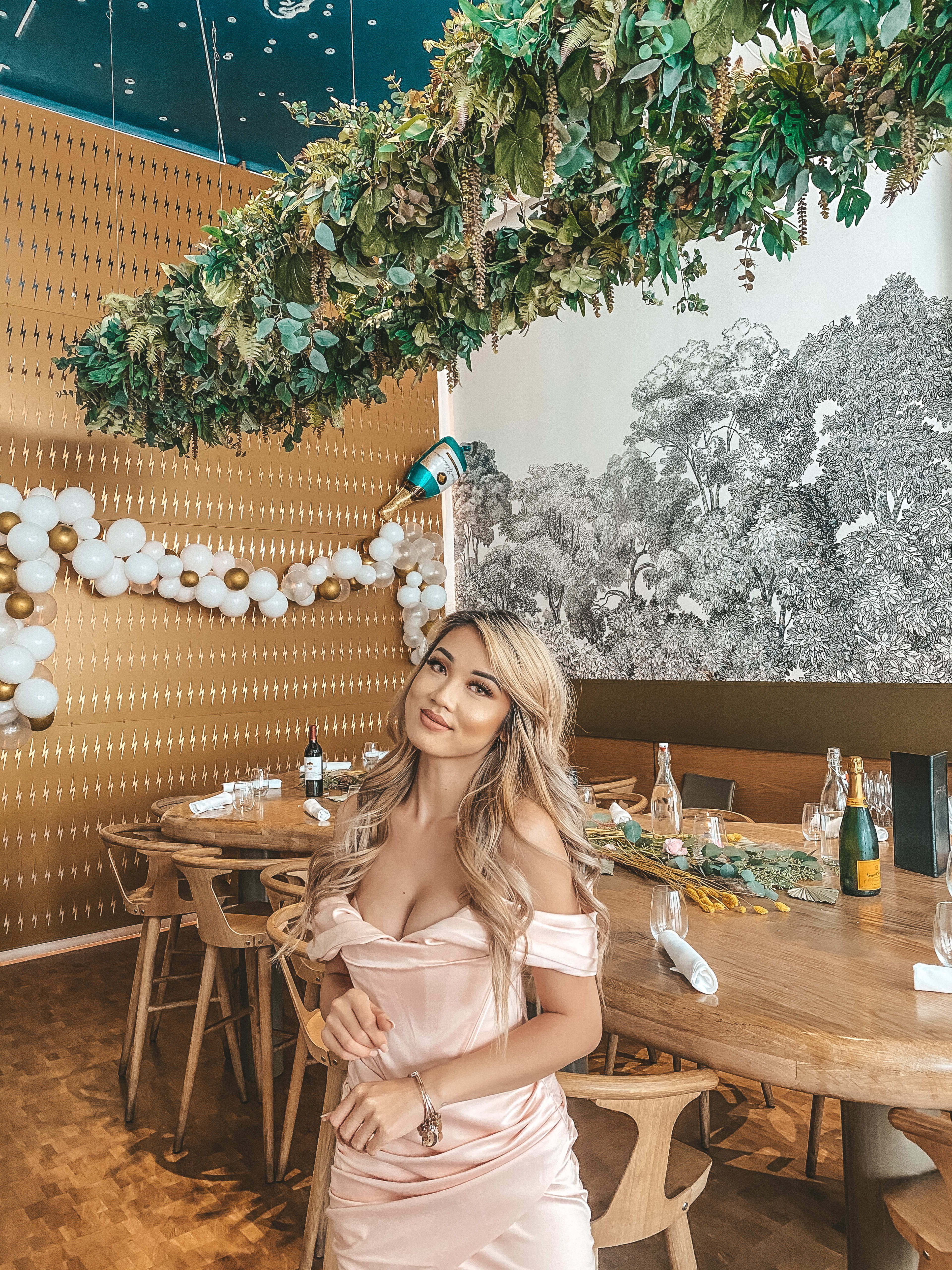 Une femme vêtue d’une robe rose pâle à une table de dîner.