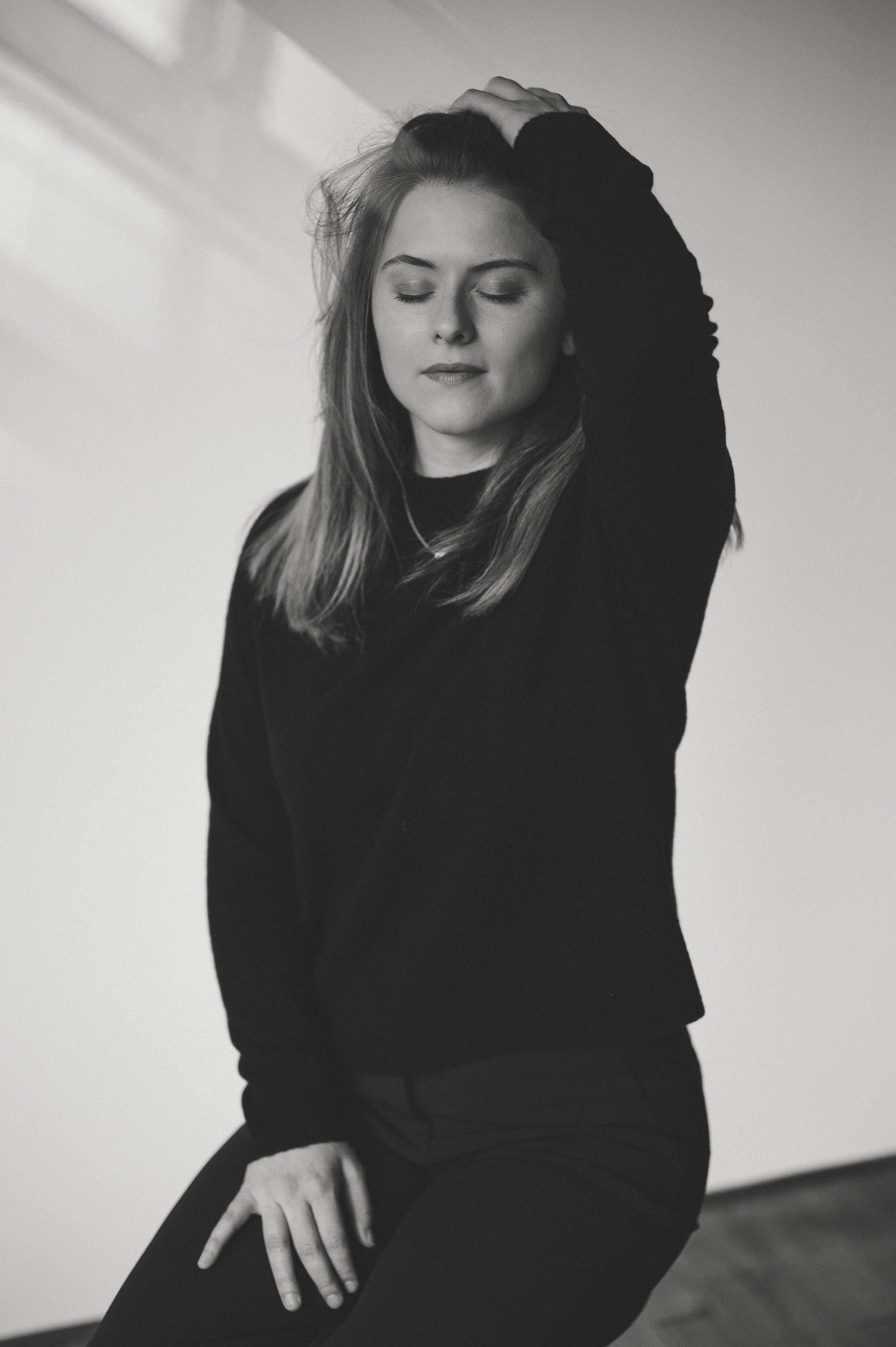 A black and white photoshoot of a woman on a couch.