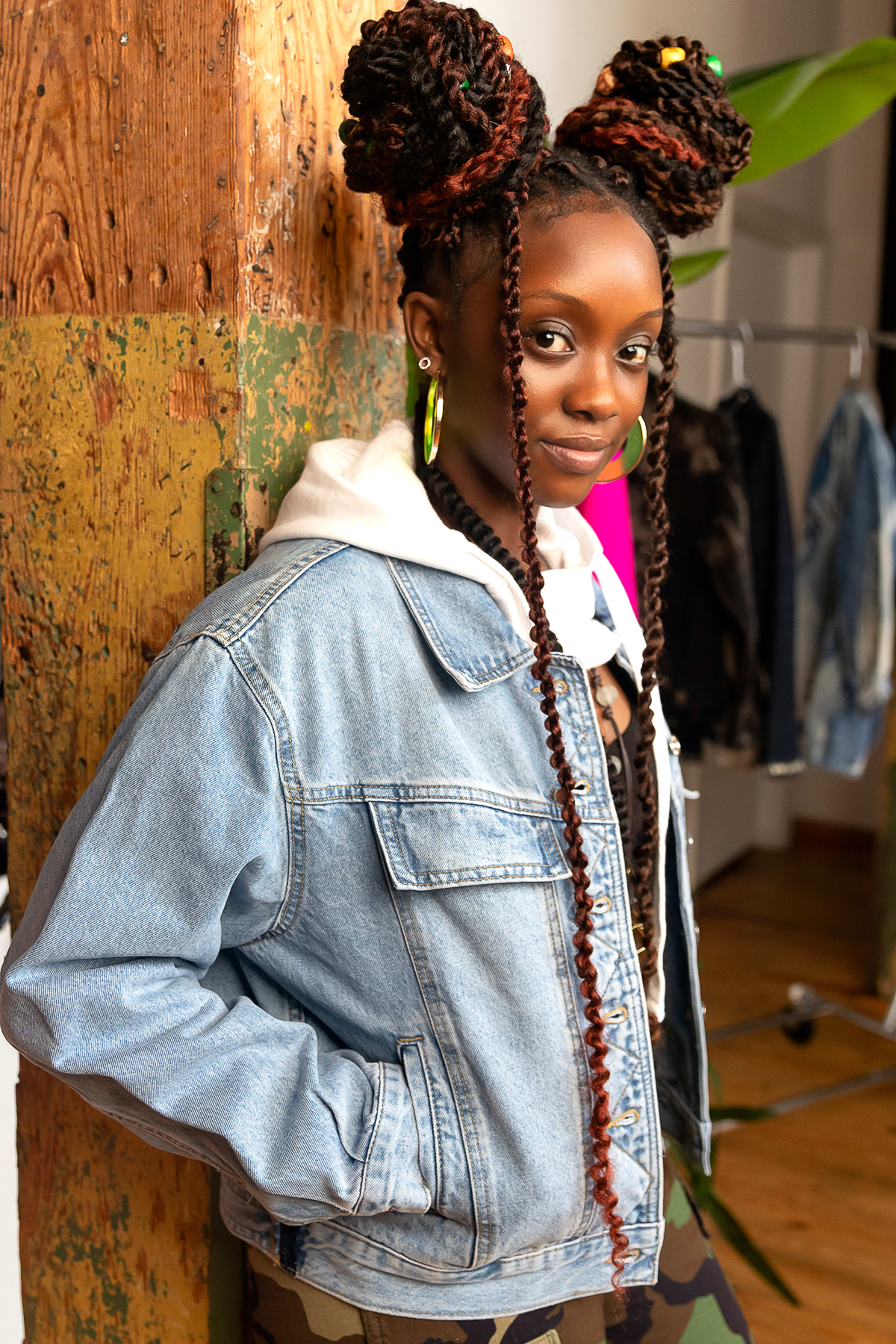 A fashion model posing next to a wooden pole for a photoshoot.