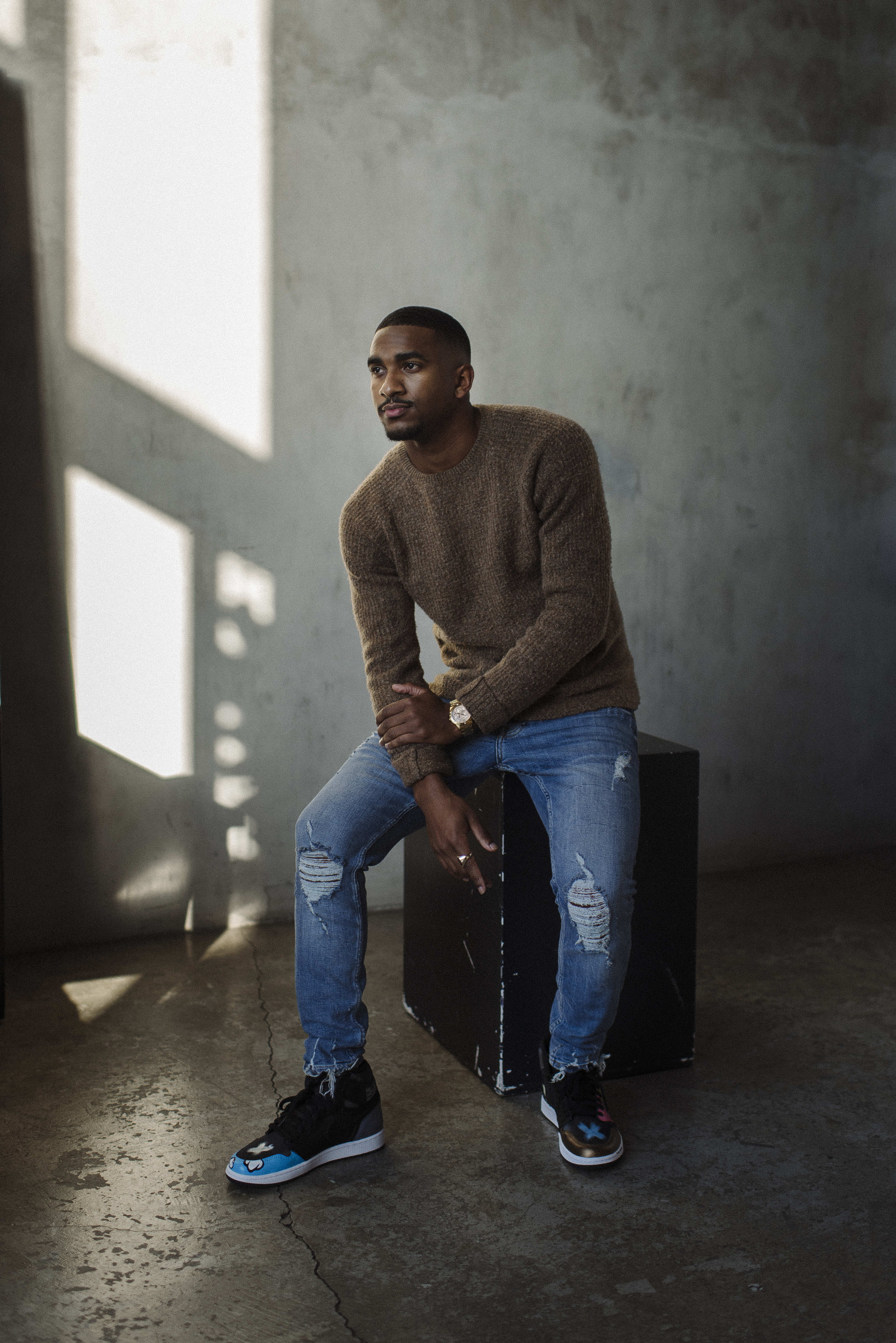 A man posing for a photo shoot on top of a black podium.