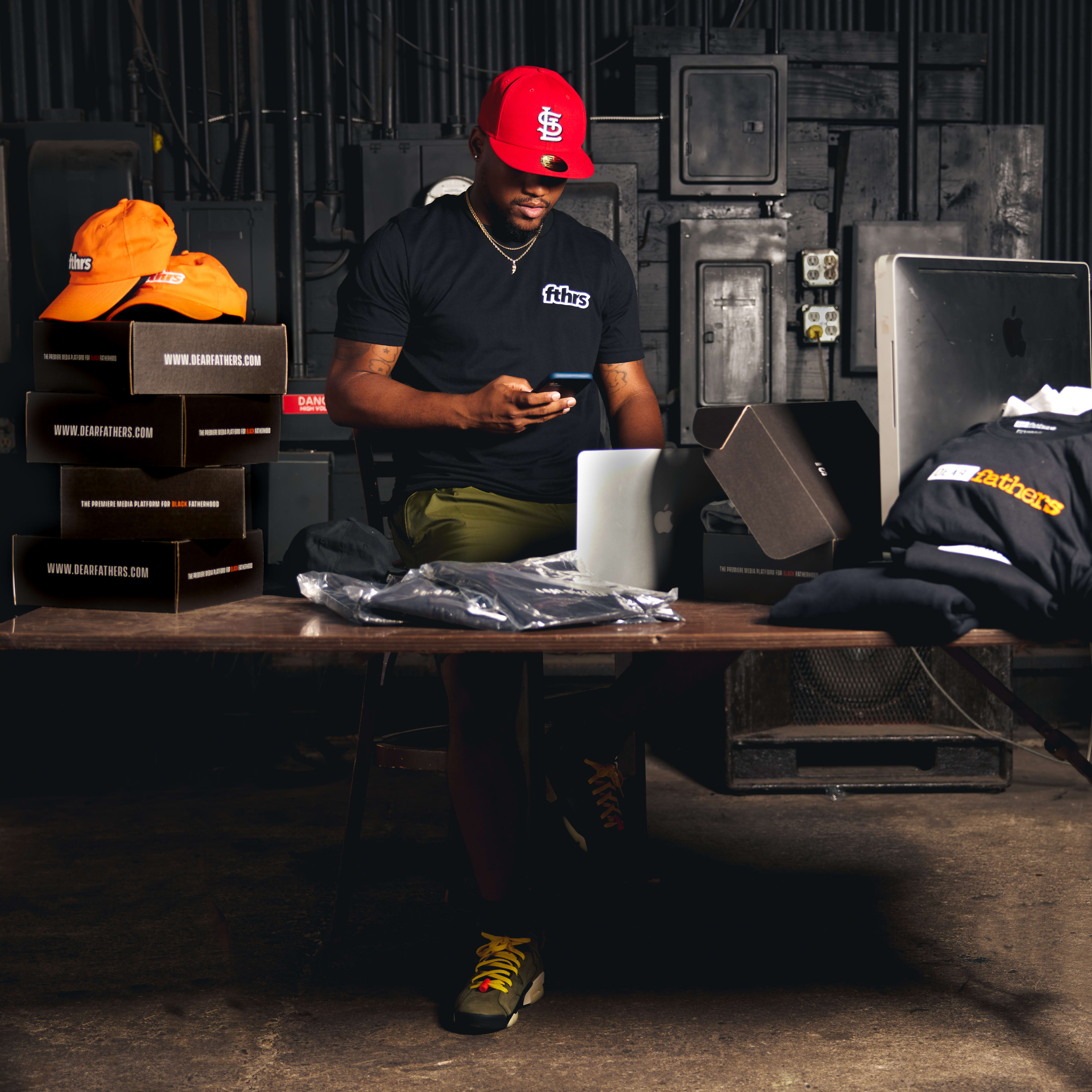 A man sitting at a table looking at his mobile phone during a photo shoot.