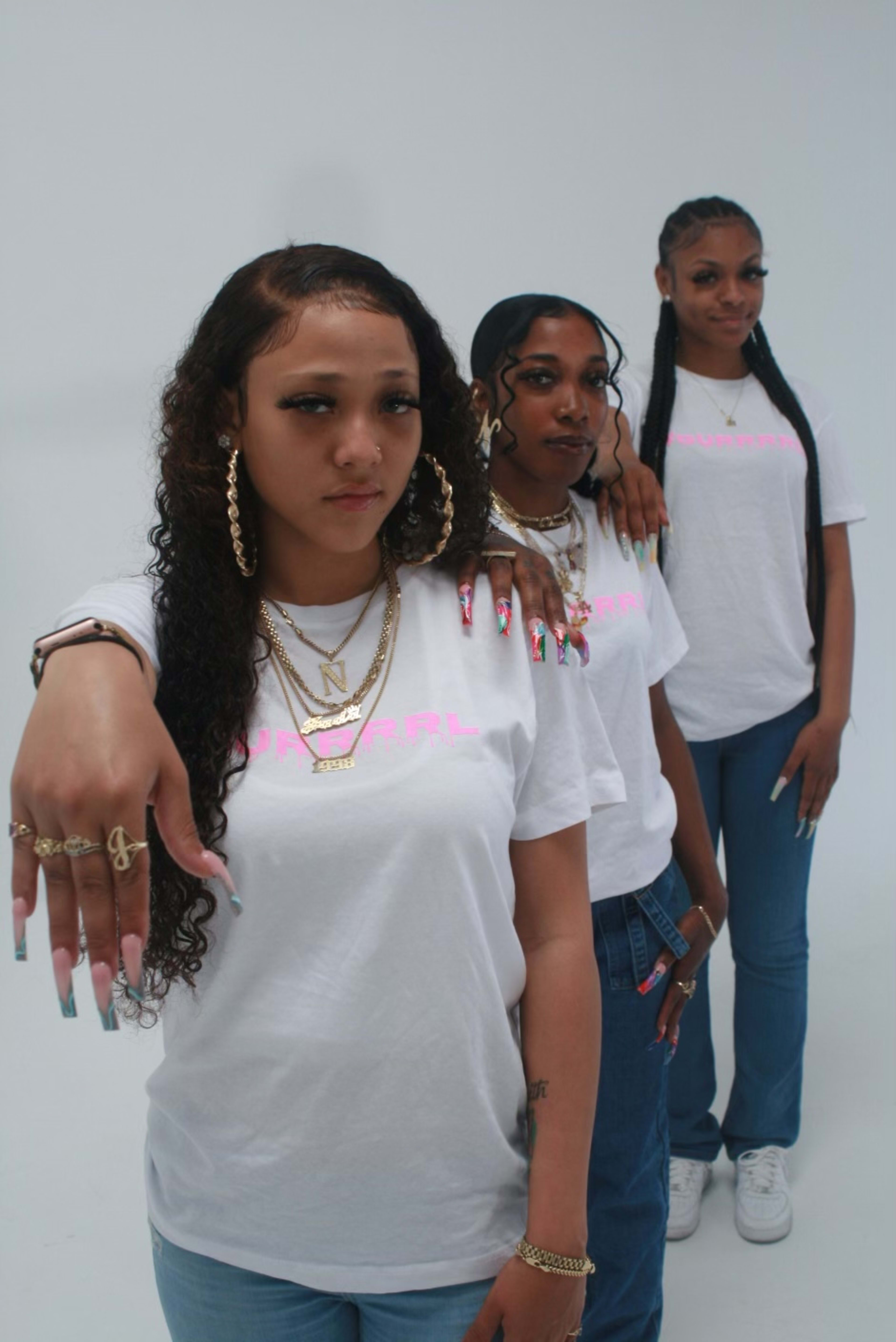 A photo shoot of young women standing next to each other, wearing white and blue products.