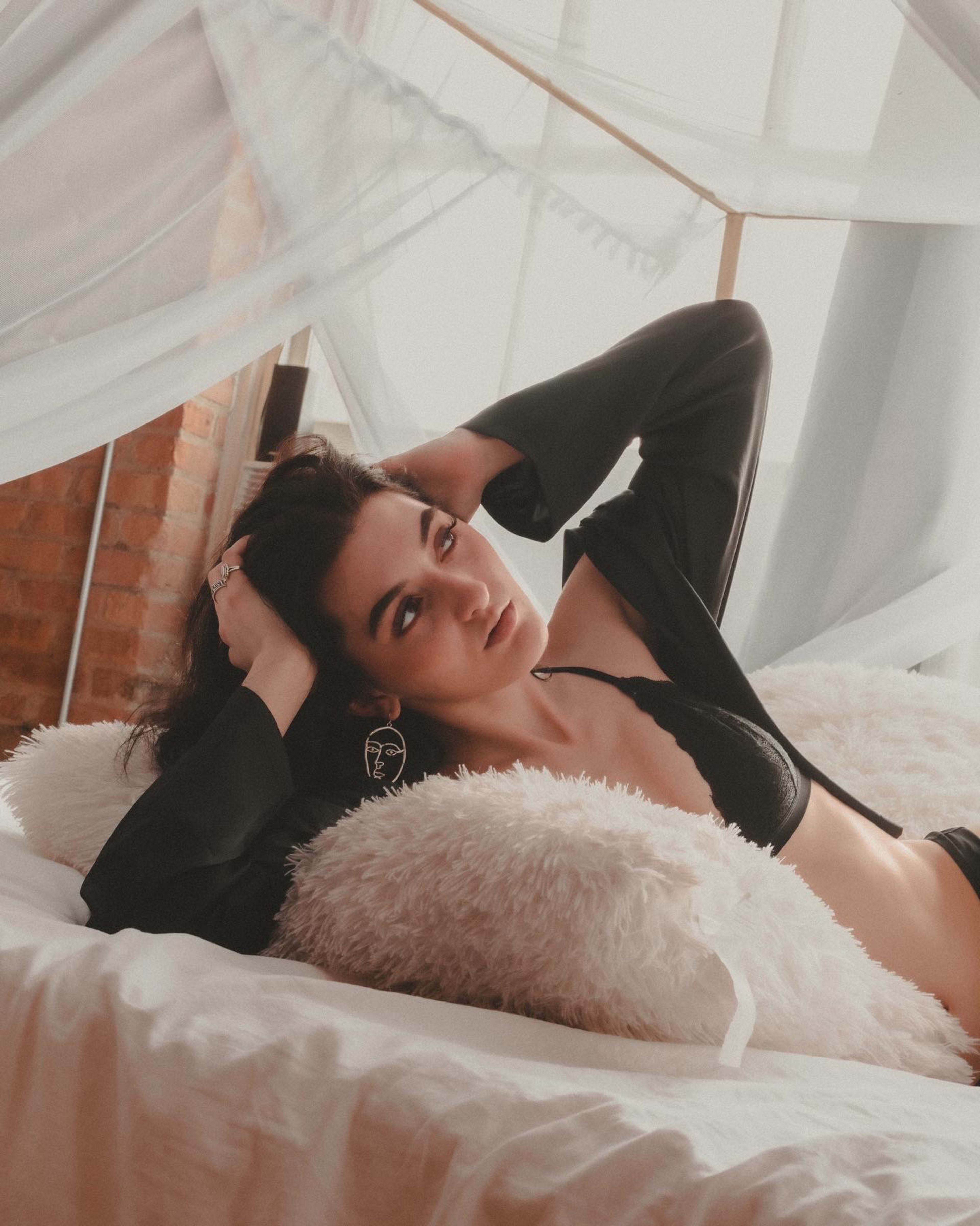 Une femme en lingerie posant sur un lit pour un shooting photo boudoir de style boho.