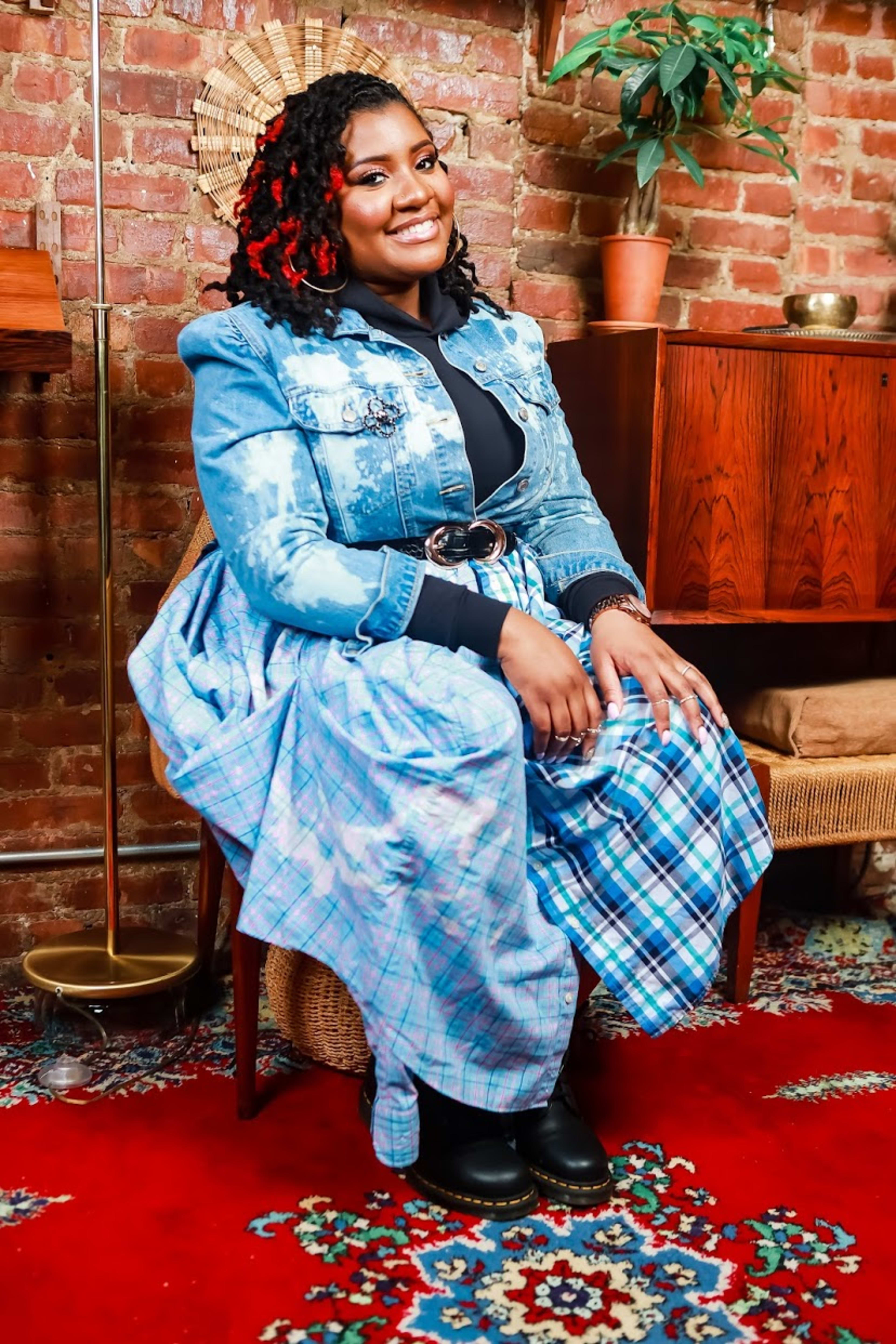 A fashion model posing on a brown chair in a blue outfit.