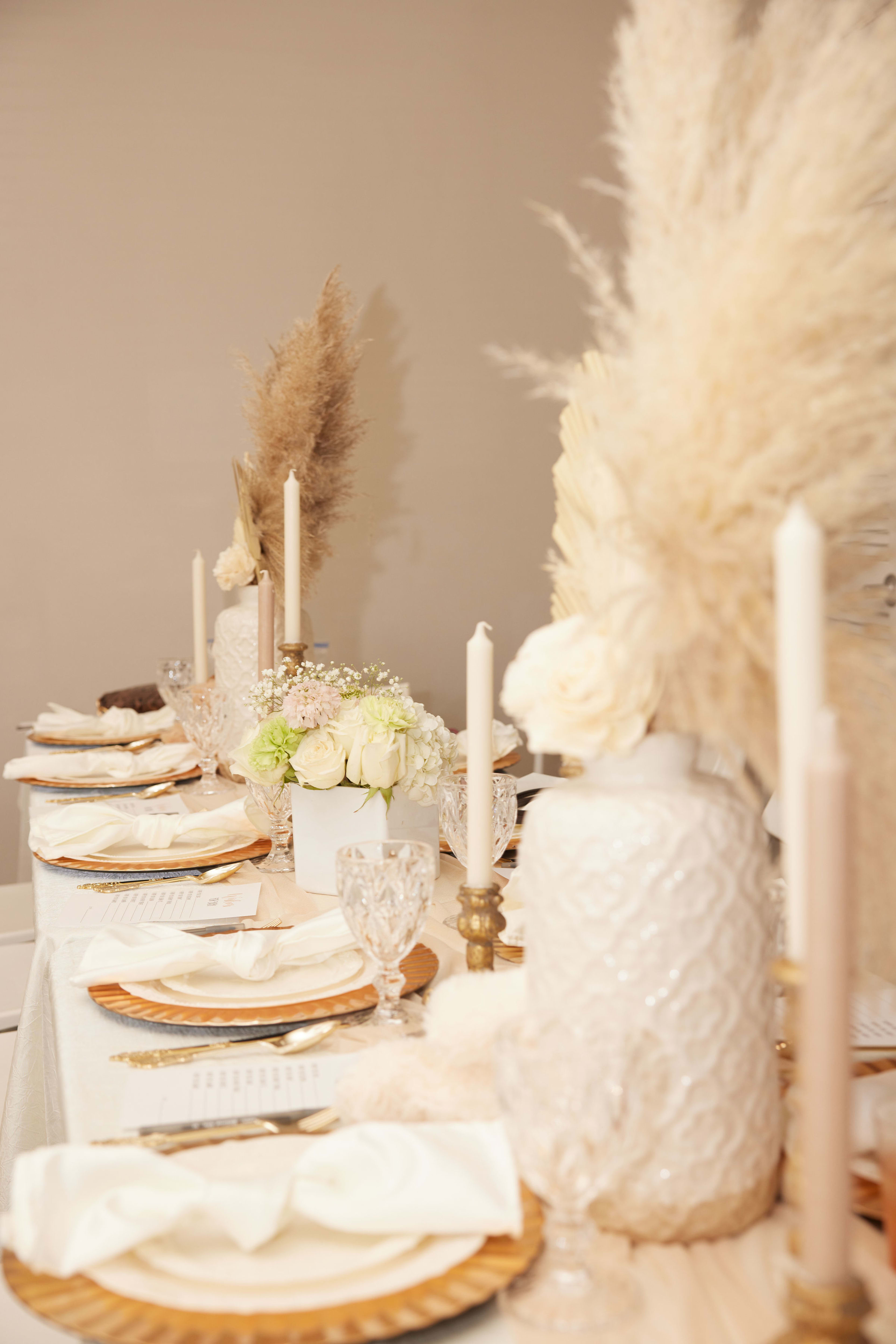 A boho-themed table set with a vase of flowers and plates.