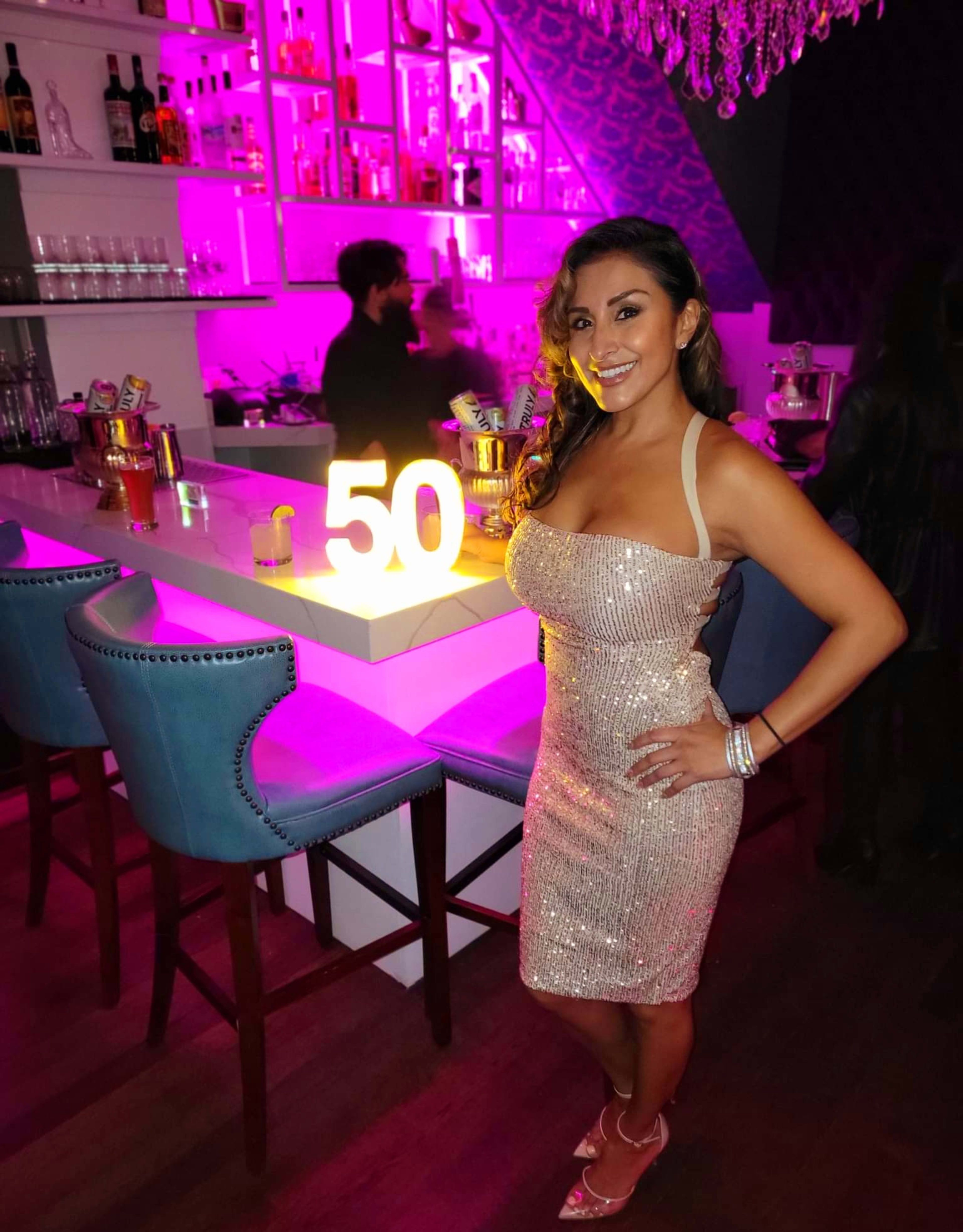 A woman standing in front of a birthday sign on a table at a party.